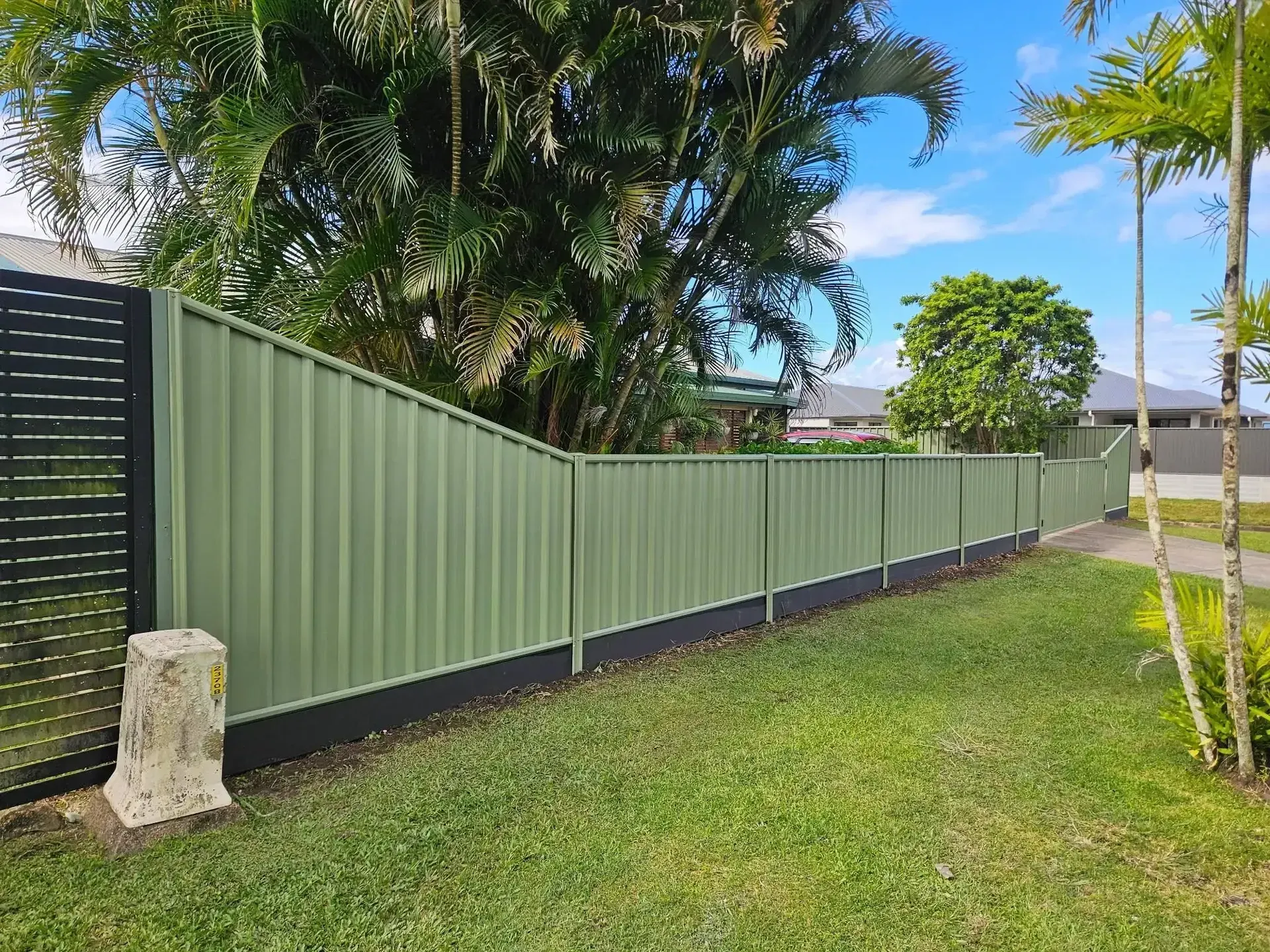 Green Corrugated Metal Fence Along a Grassy Yard — KLS Fencing In Mossman, QLD