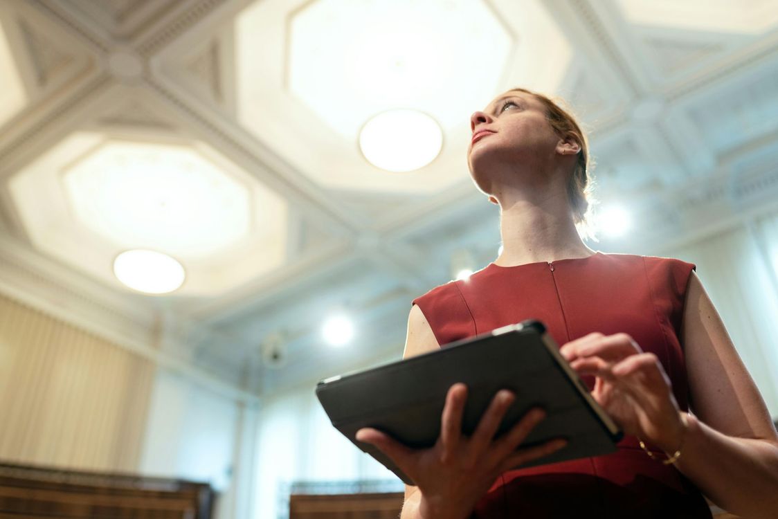 Donna con top rosso che tiene in mano un tablet e guarda verso il soffitto decorato con luci rotonde controllo domotica luci