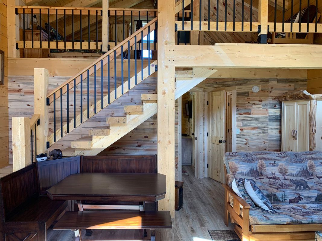 A living room in a log cabin with stairs leading up to the second floor.