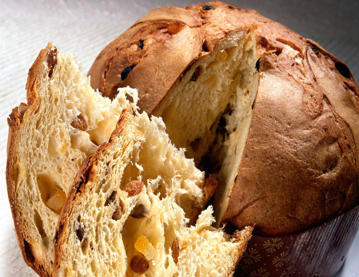 Pagnotta di pane appena sfornata con una fetta che mostra una mollica morbida e ariosa e una crosta dorata.