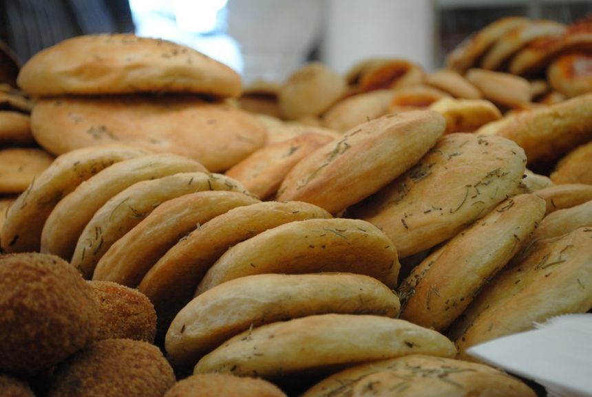 Assortimento di pagnotte e panini freschi impilati in una vetrina da panetteria.