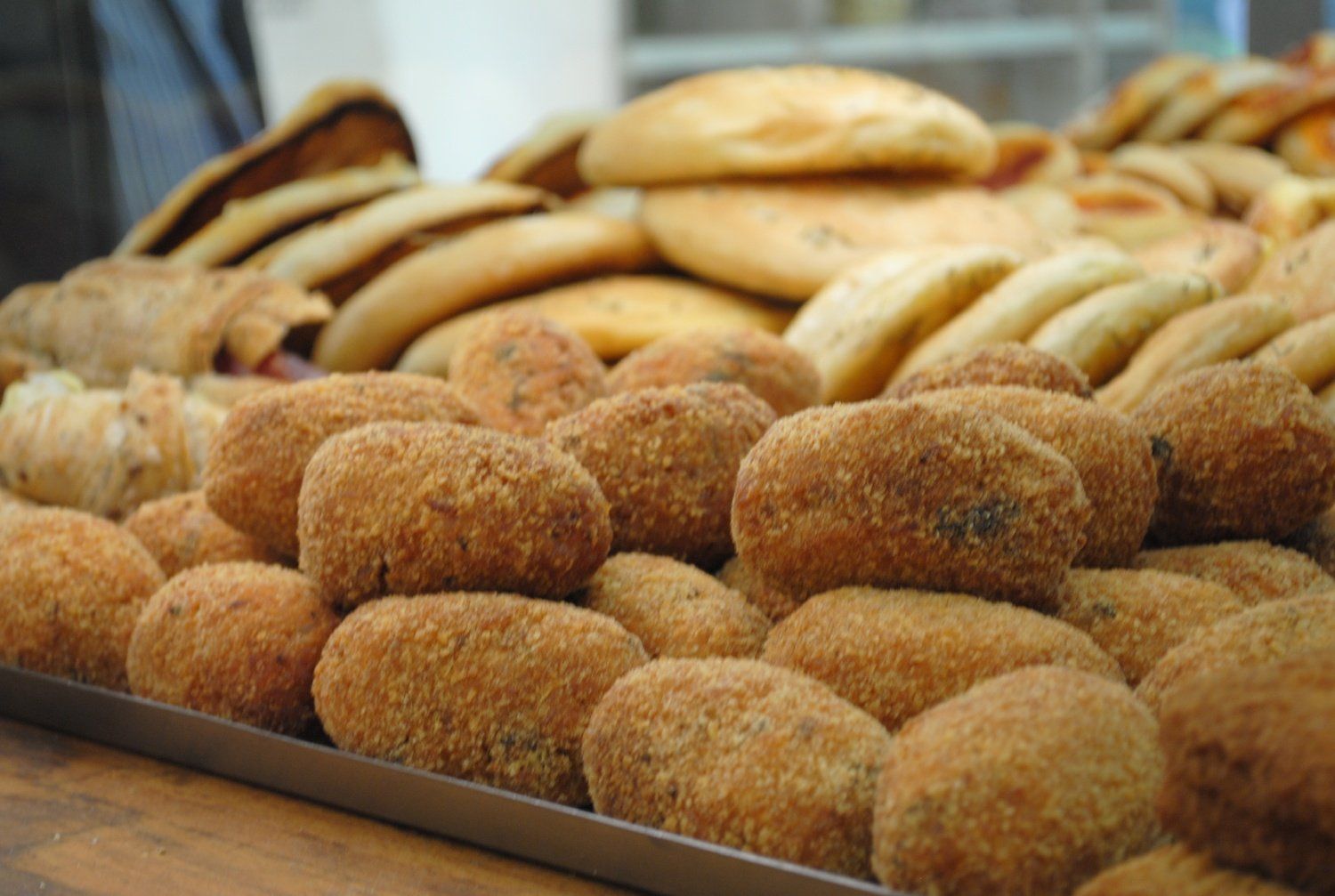 Esposizione in panetteria di un assortimento di pagnotte e panini appena sfornati su vassoi.
