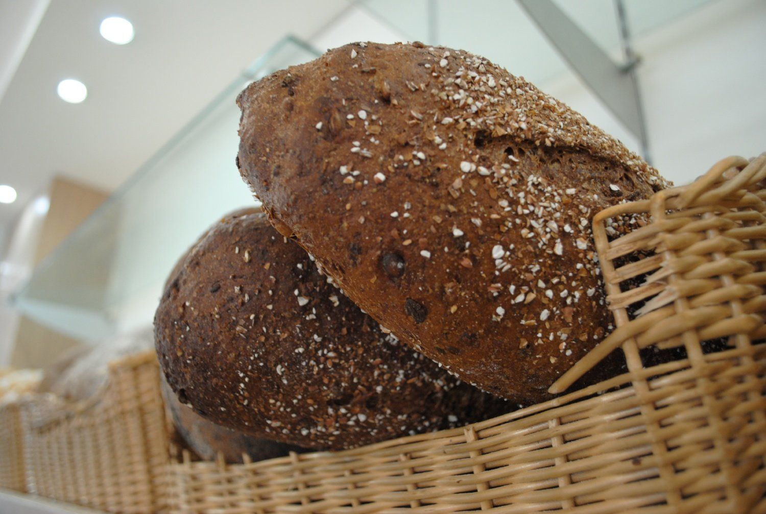 Due pagnotte di pane scuro in un cesto di vimini, cosparse di semi e farina.