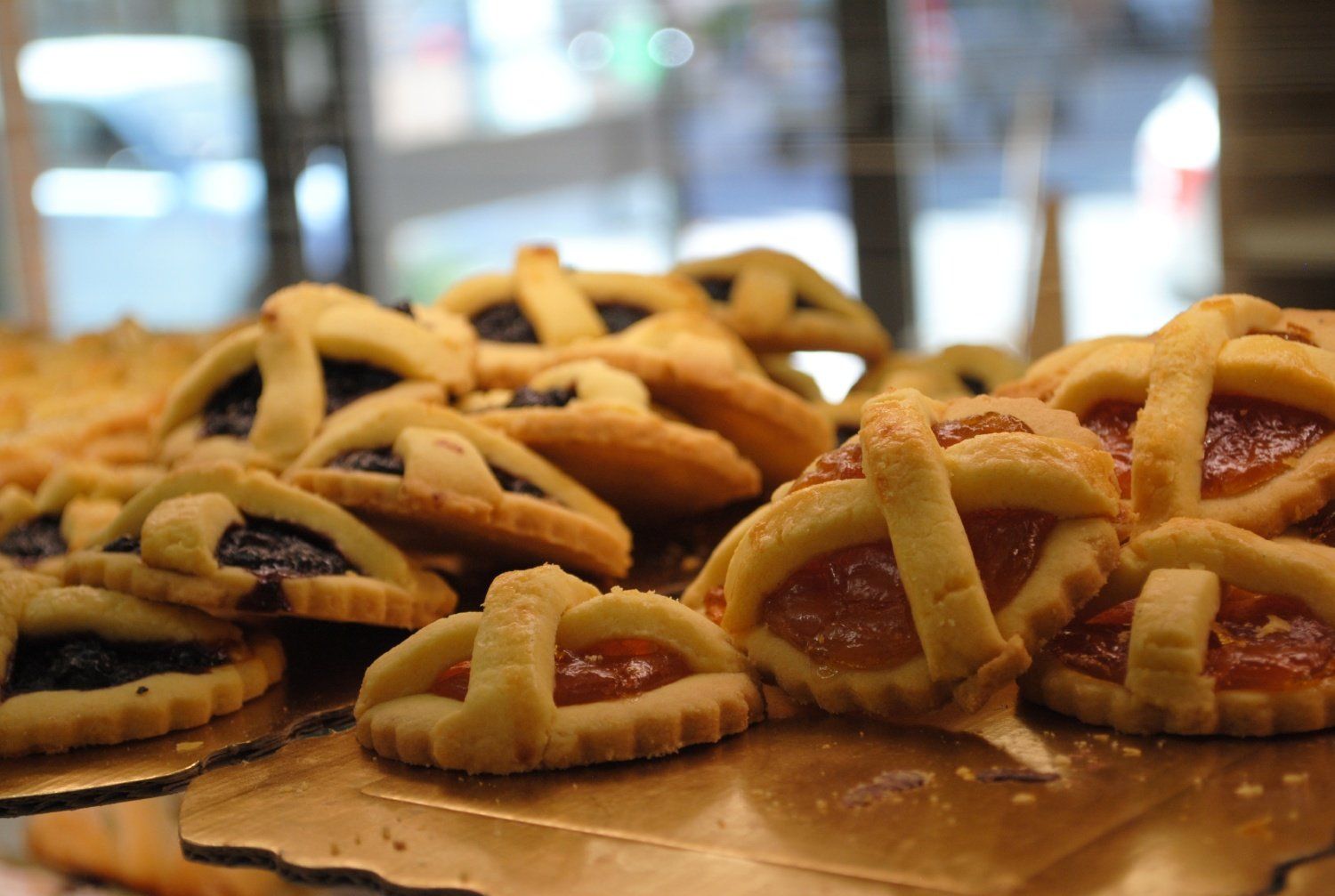 Un vassoio di pasticcini dorati a forma di griglia con ripieno scuro sul bancone di una pasticceria.
