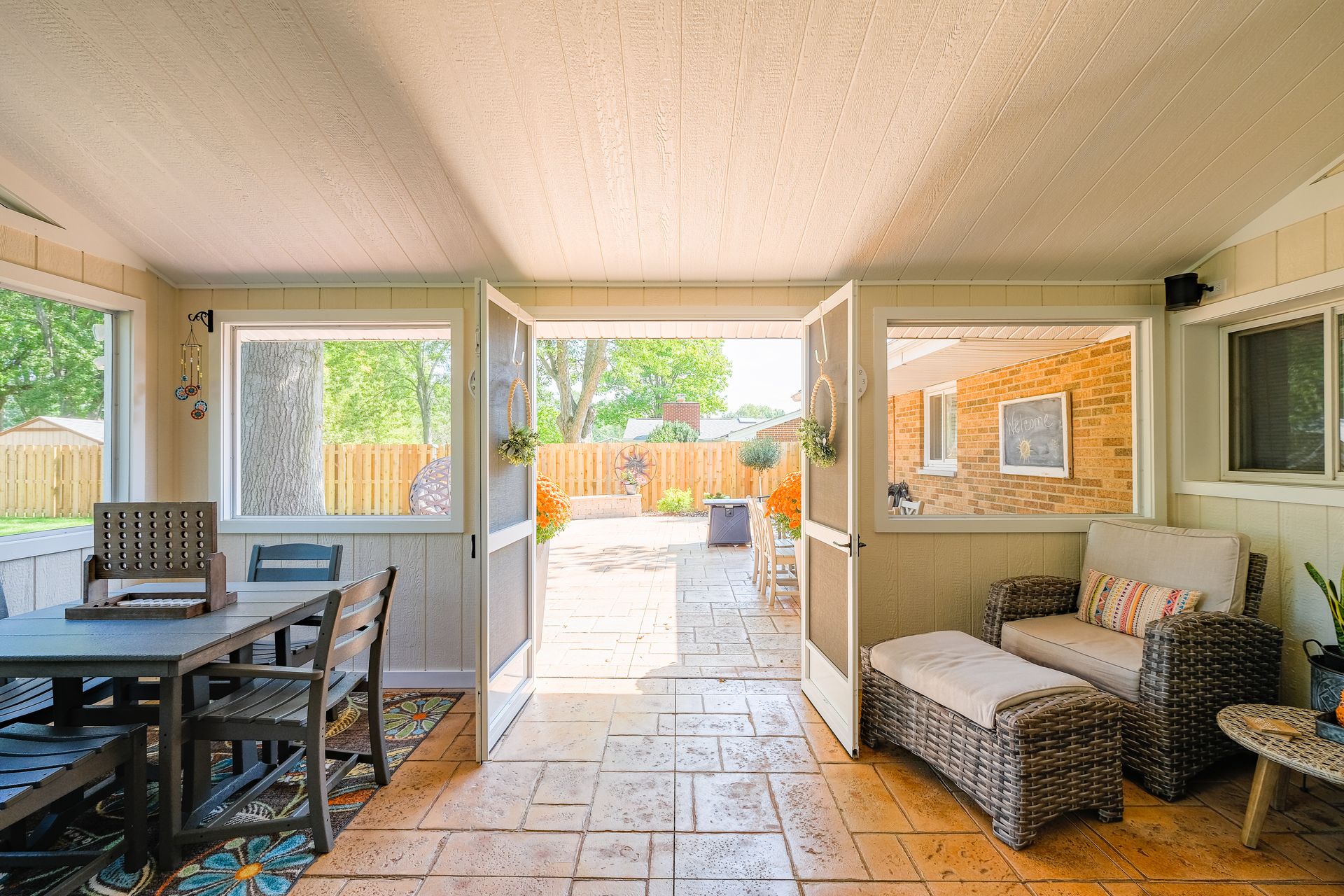 Sunroom with open doors to a backyard; furniture, stone patio.