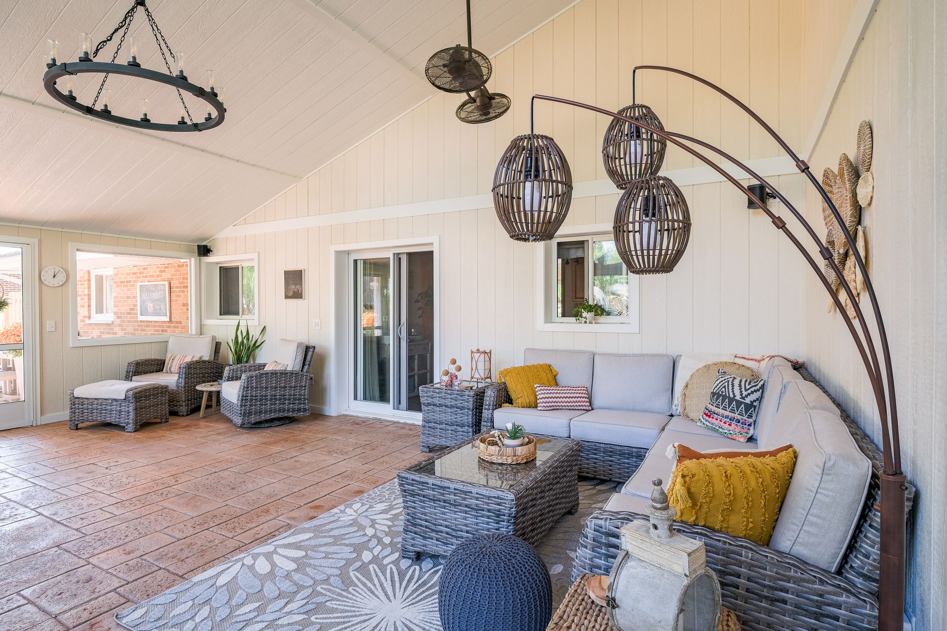 Covered patio with wicker furniture, rug, and hanging lights.