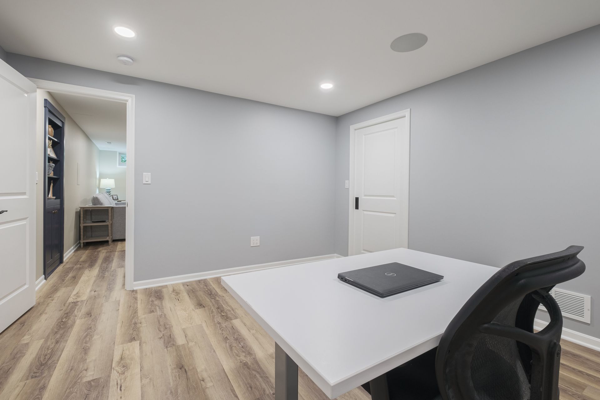 There is a desk with a laptop on it in the middle of the room.