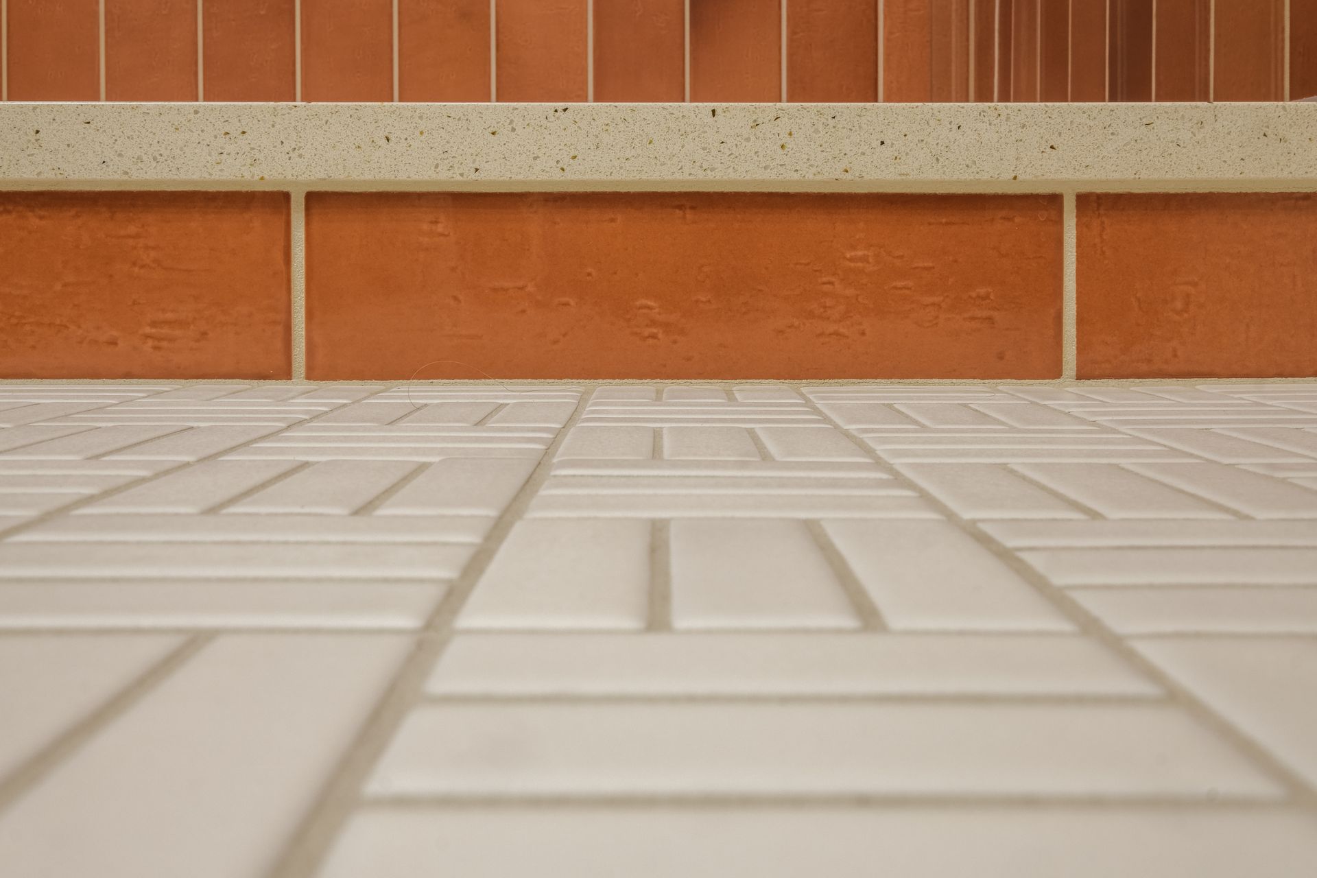 White tile floor with brick wall and decorative border.