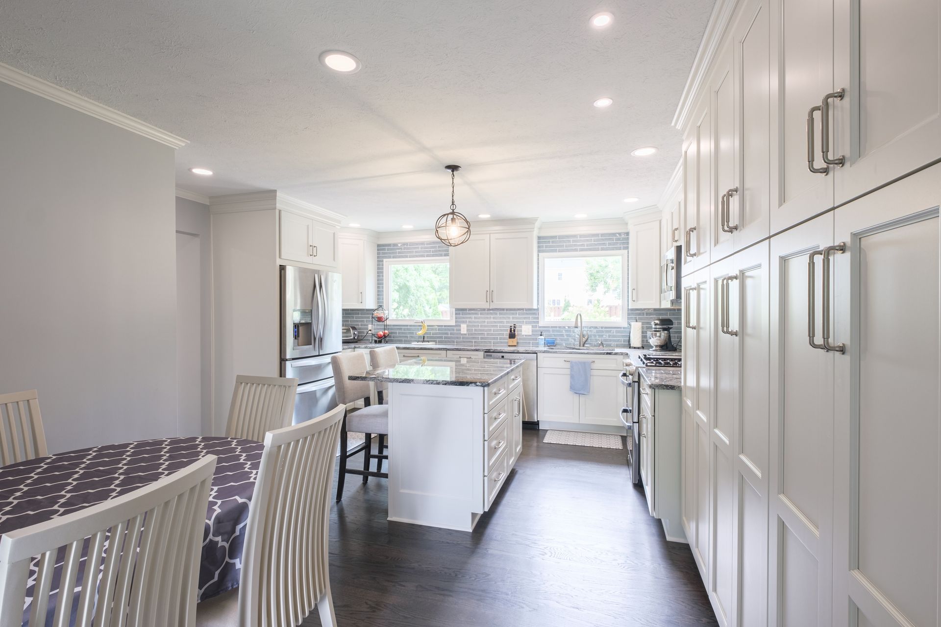 White kitchen with island, cabinets, and dining table set.