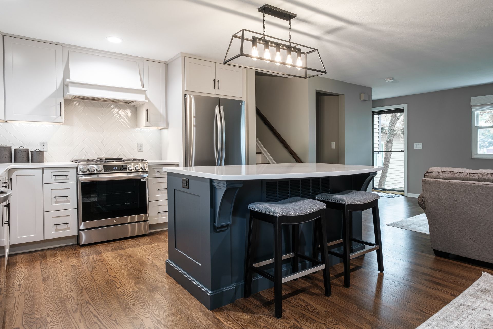 A kitchen with a large island and stools in it.