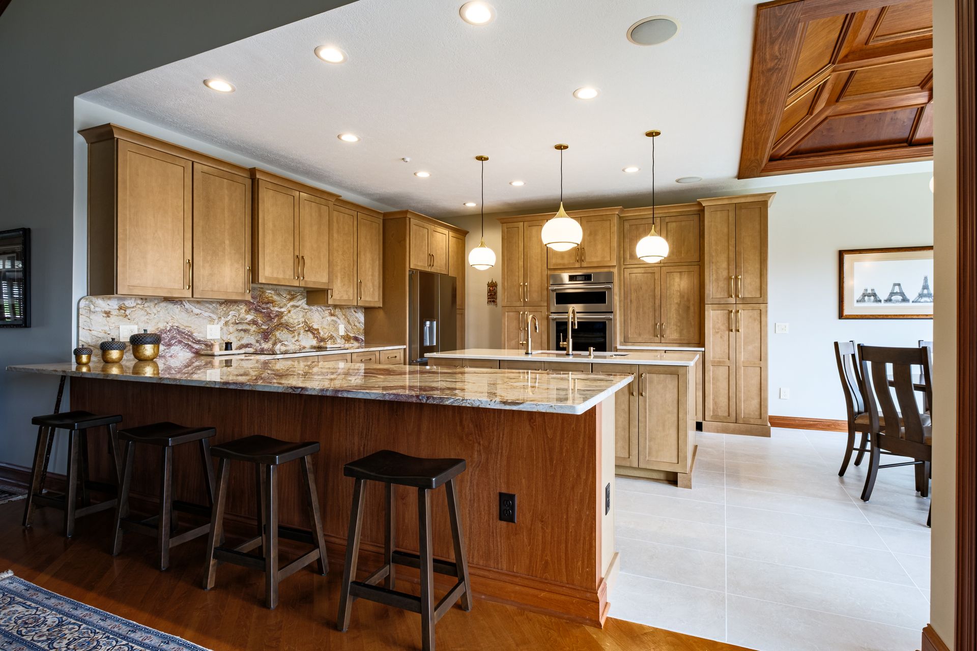 Kitchen with wooden cabinets, granite countertops, island with seating, and dining area.