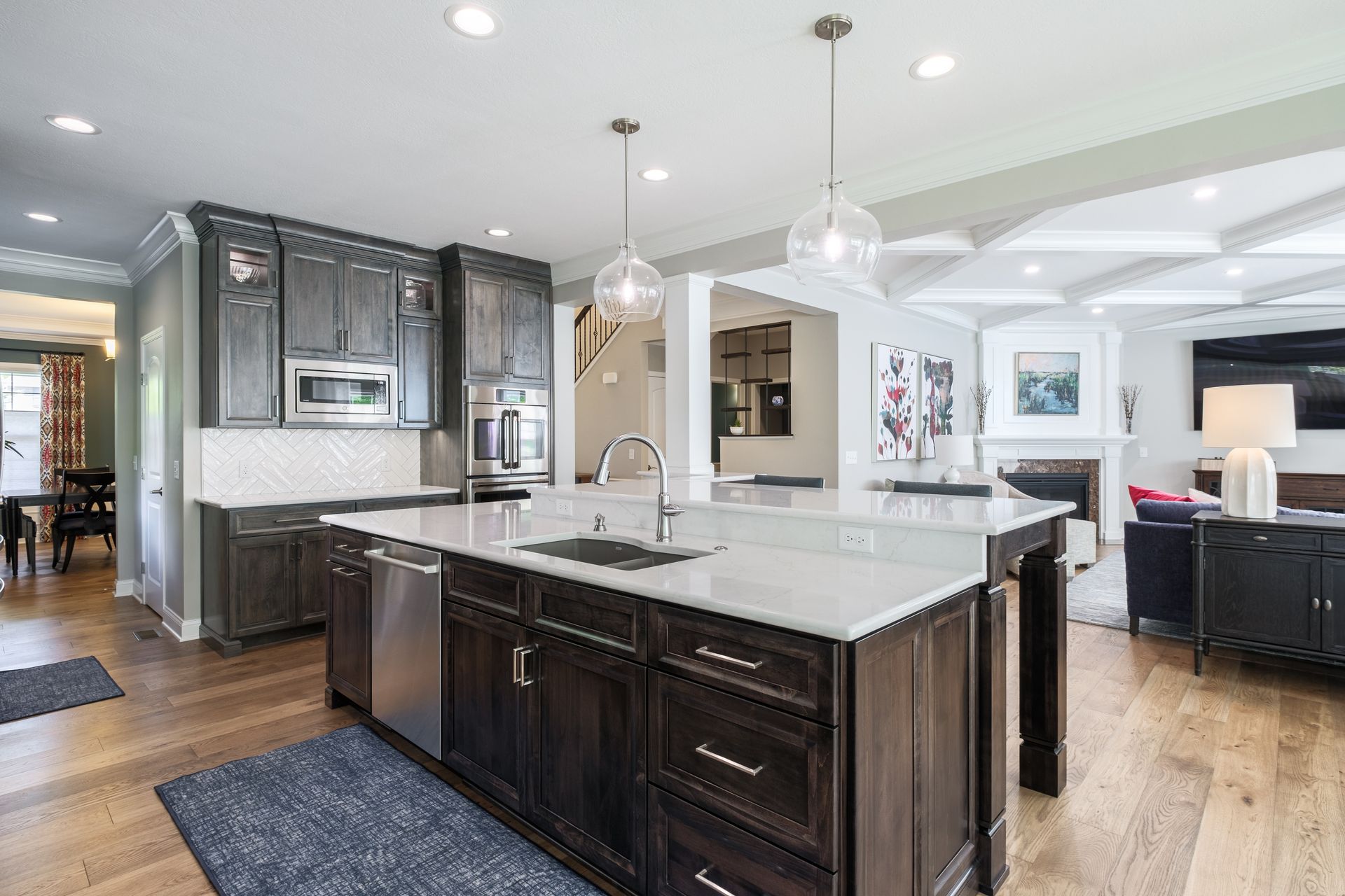 Modern kitchen with dark cabinetry, white countertops, and an island. Hardwood floors and recessed lighting.