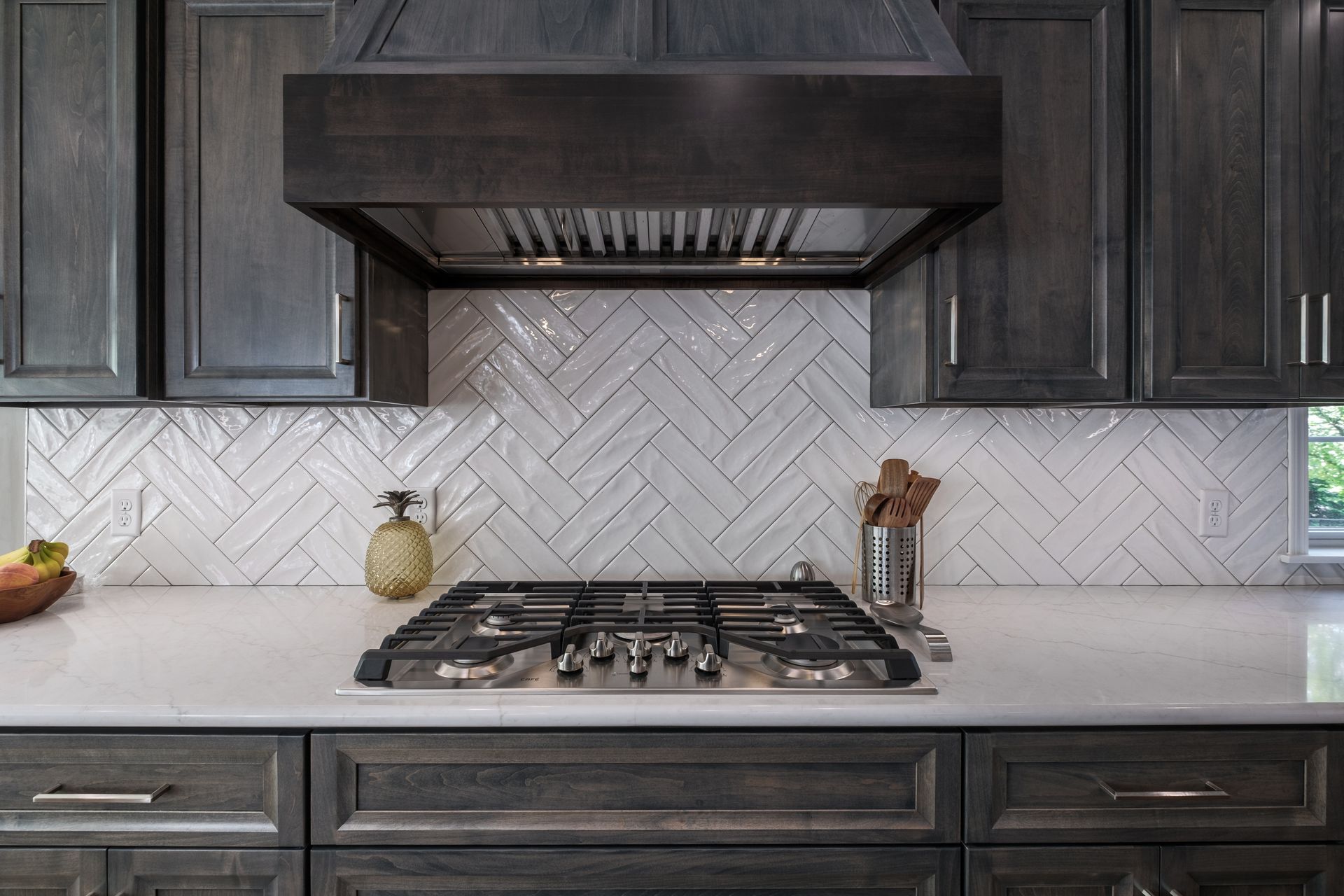 Gray kitchen with a stove, white backsplash, and dark cabinets.