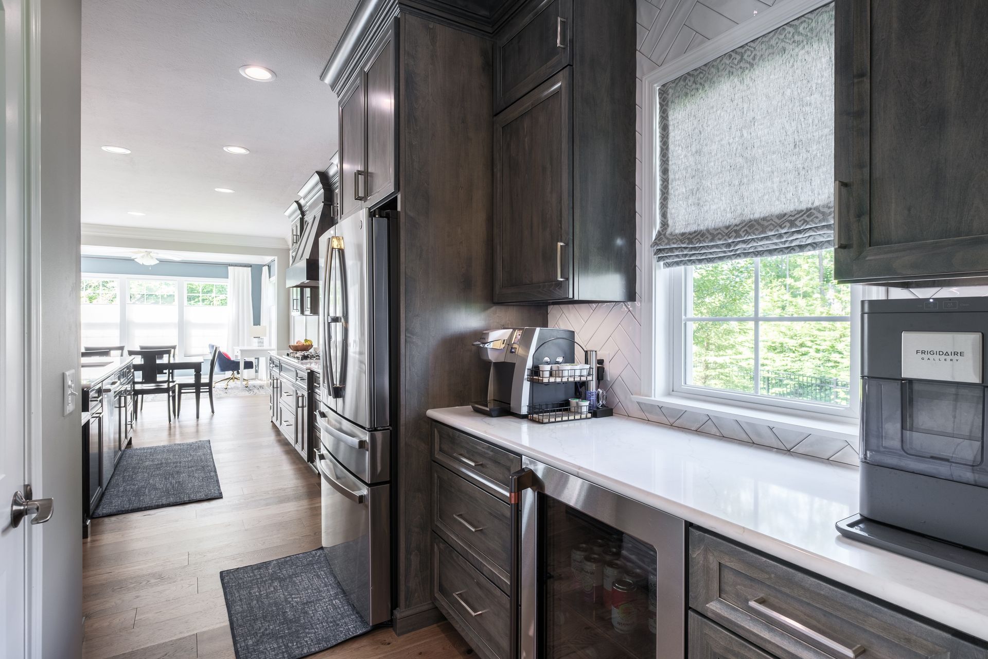 Gray kitchen with stainless steel appliances, white countertops, and a window.