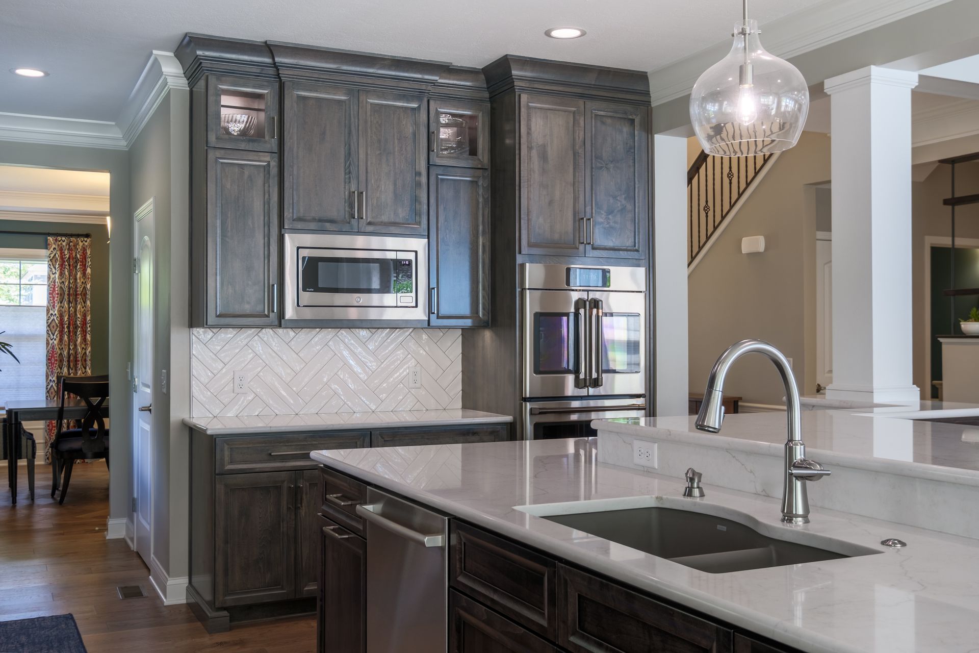 Kitchen with dark gray cabinets, white countertops, stainless steel appliances, and a hanging light.