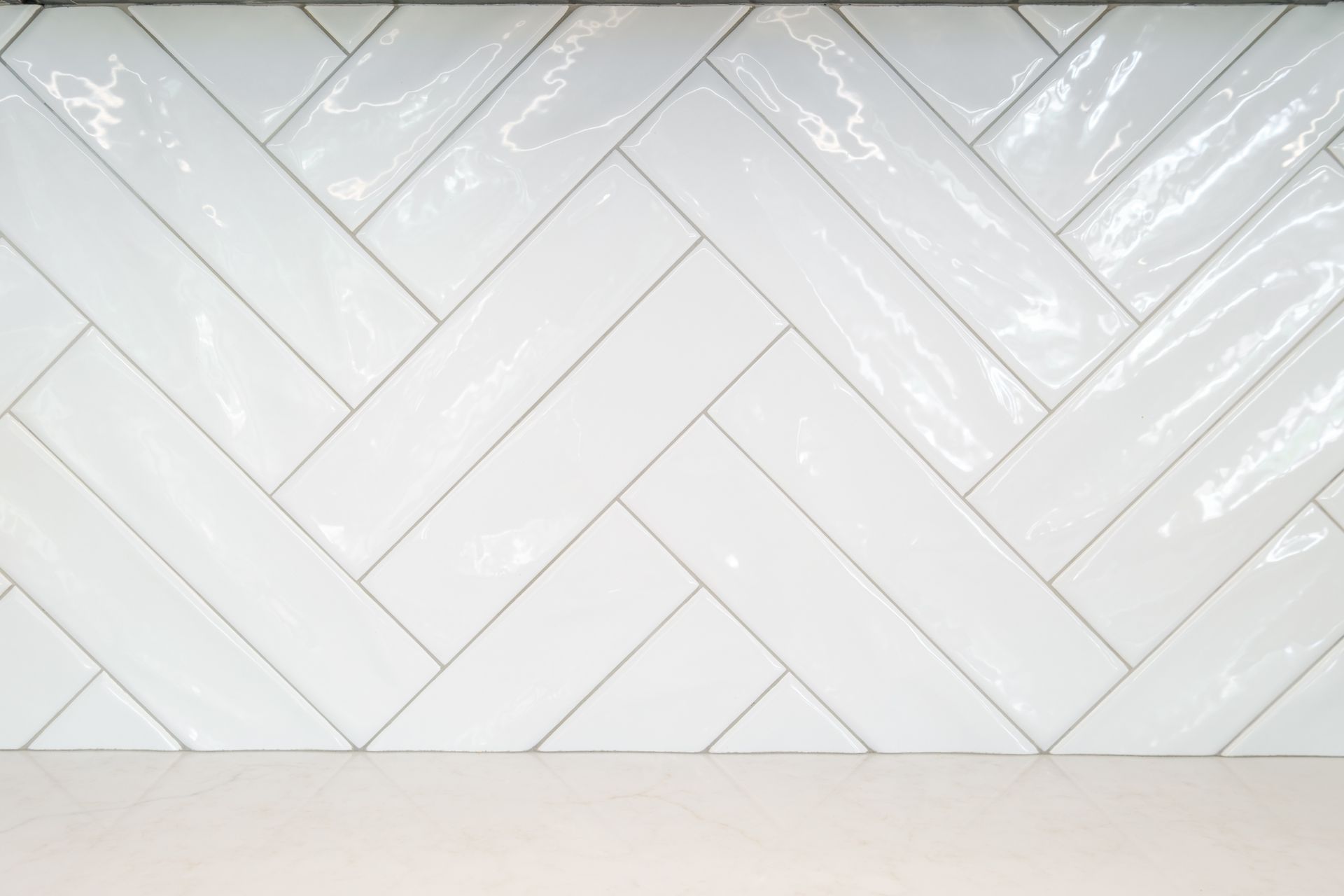 White herringbone tile backsplash above a neutral countertop.