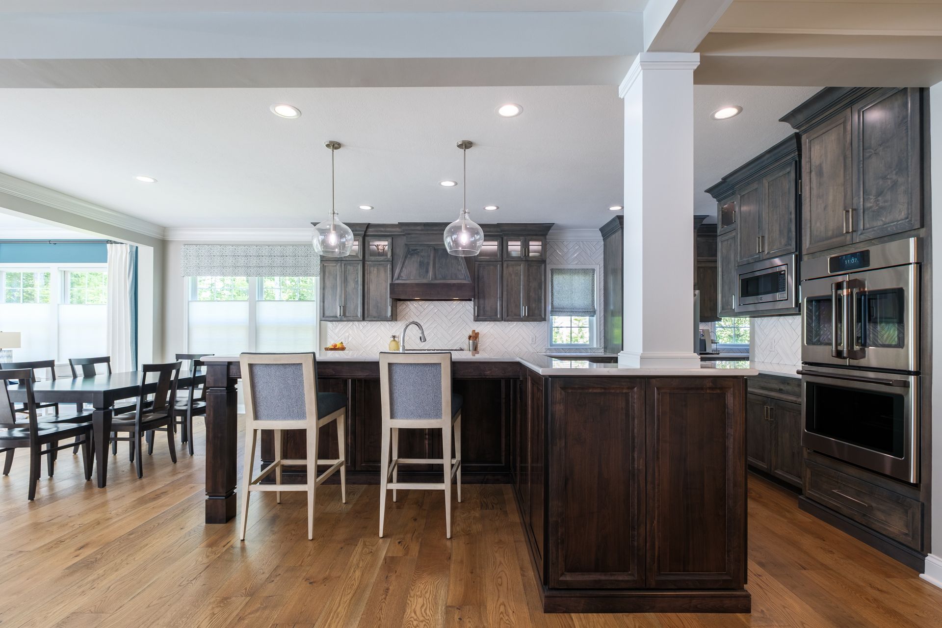 Kitchen with dark wood cabinets, island with bar stools, and dining area.