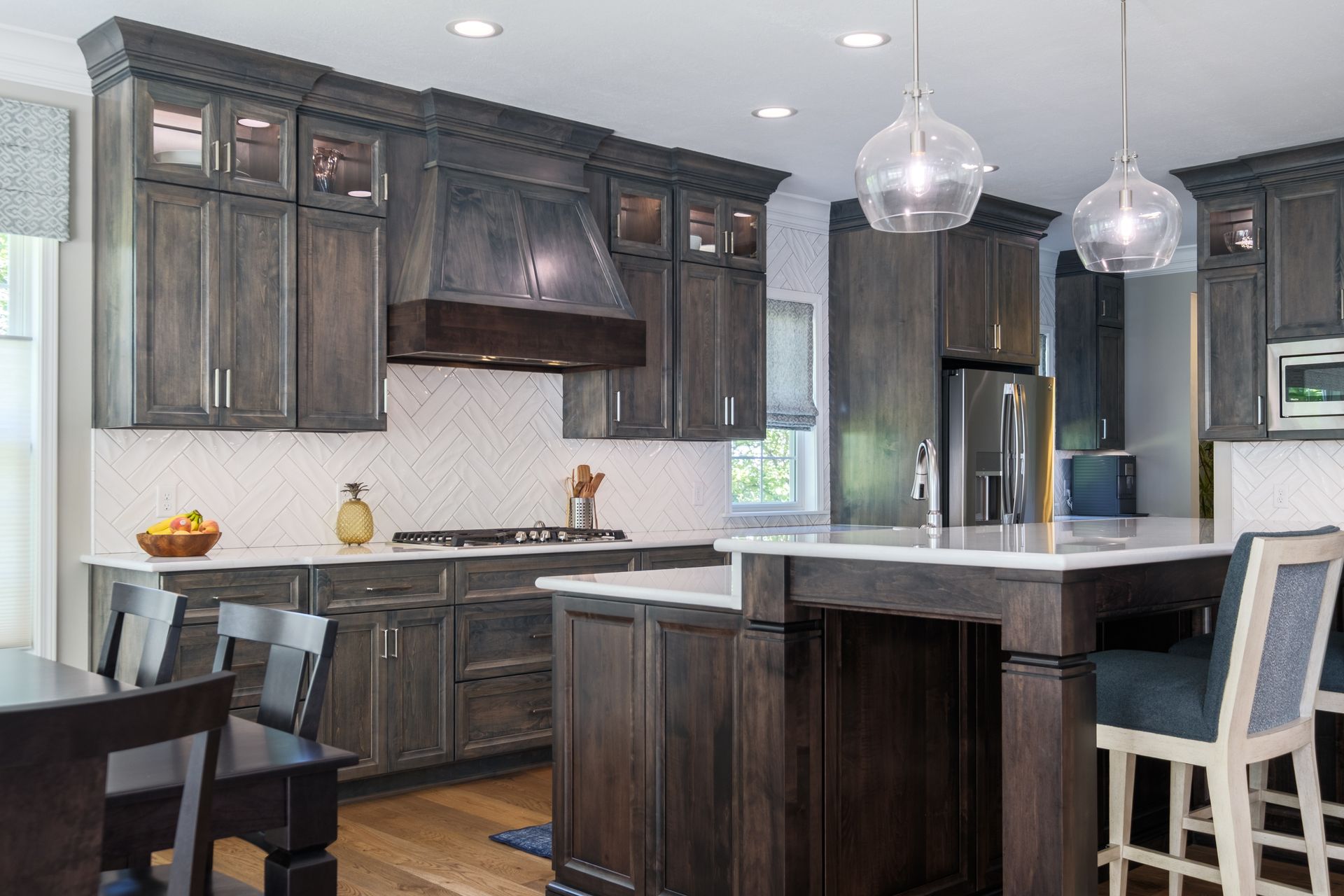 Dark wood kitchen with island, white counters, and glass pendant lights.