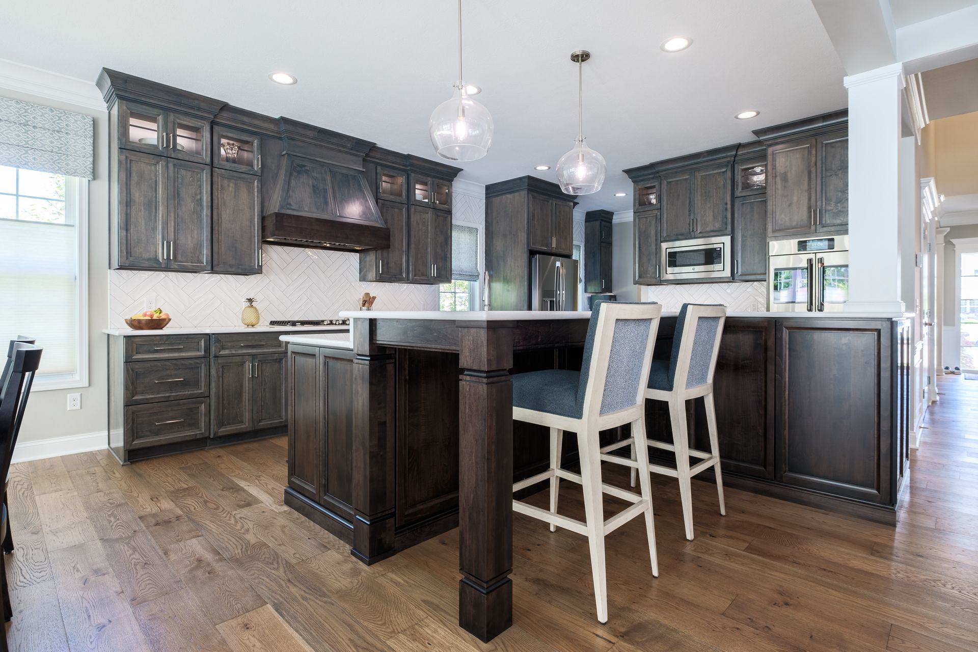 Kitchen with dark wood cabinets, island, and bar stools.