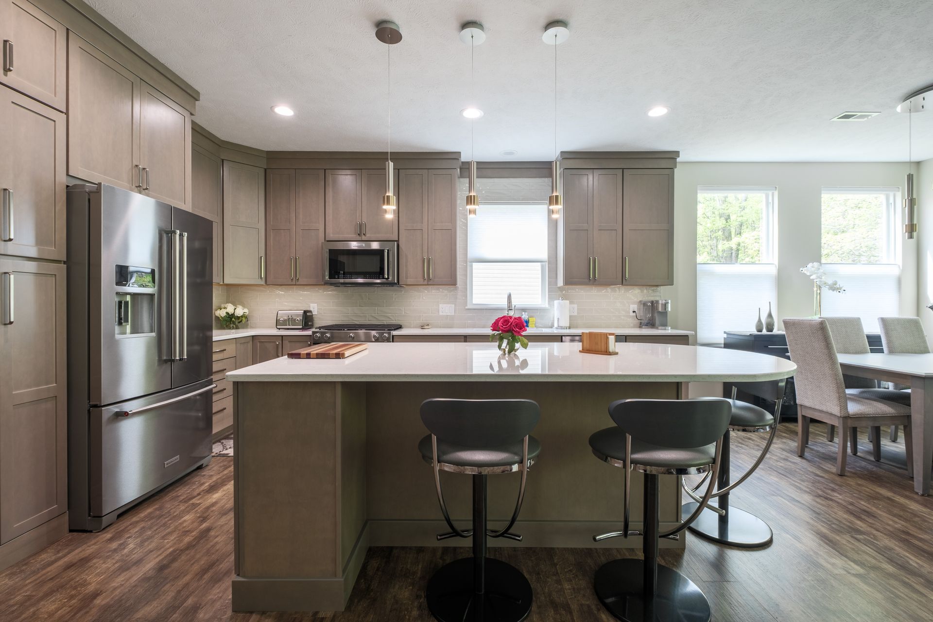 Modern kitchen with gray cabinets, stainless steel appliances, and a white island with bar stools.