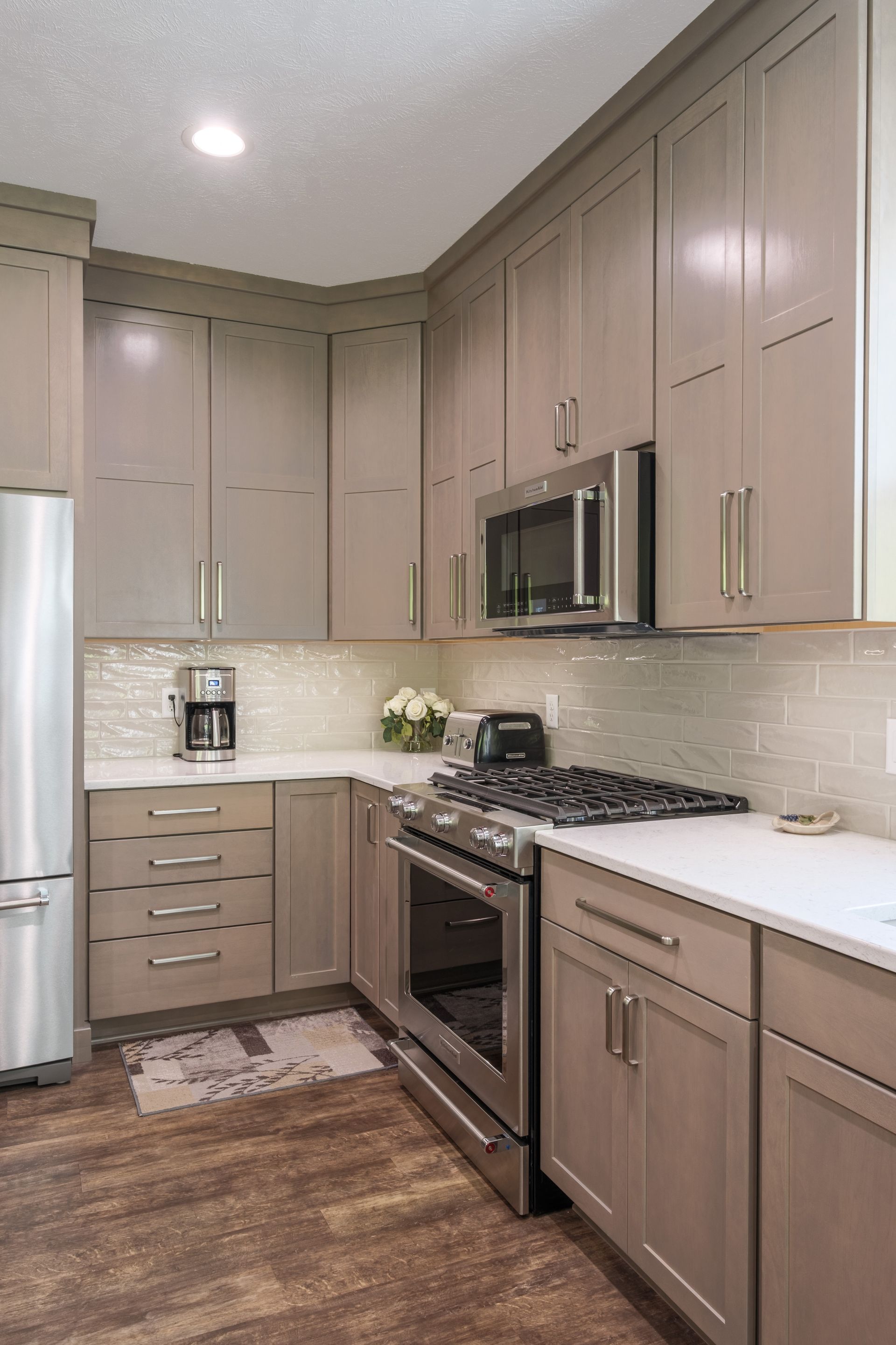 Modern kitchen with light gray cabinets, stainless steel appliances, and white countertops.