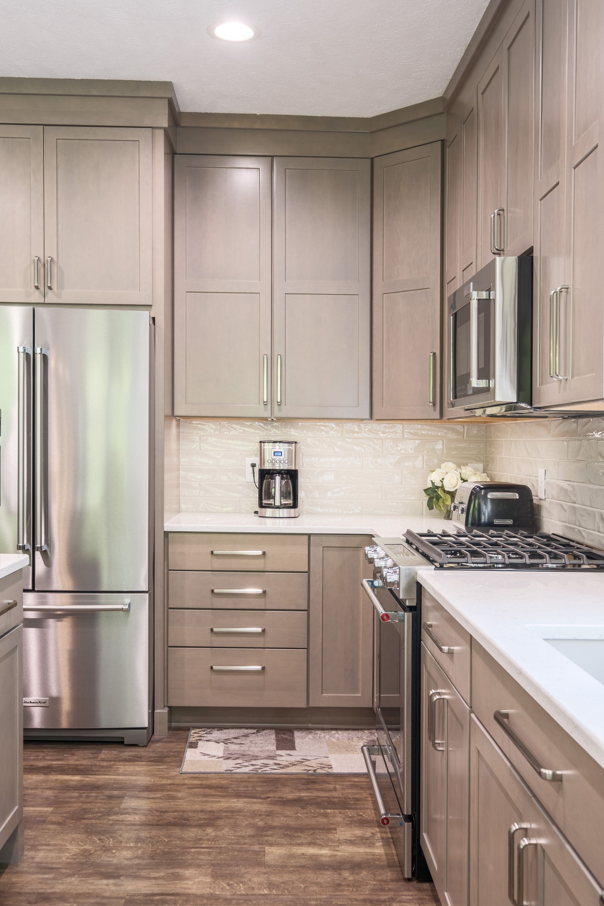 Modern kitchen with beige cabinets, stainless steel appliances, and white countertops.