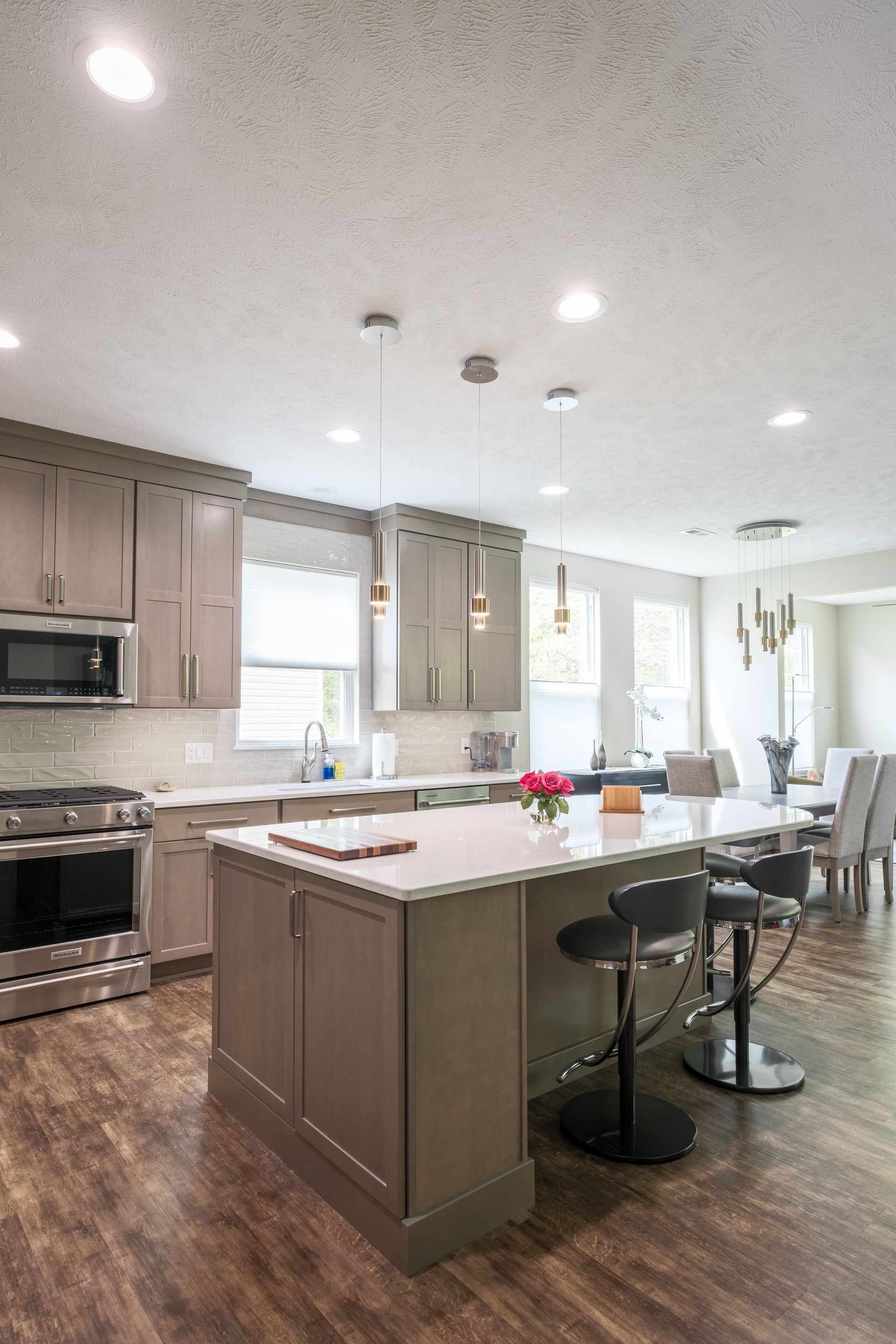Modern kitchen with gray cabinets, stainless steel appliances, and an island with bar stools.
