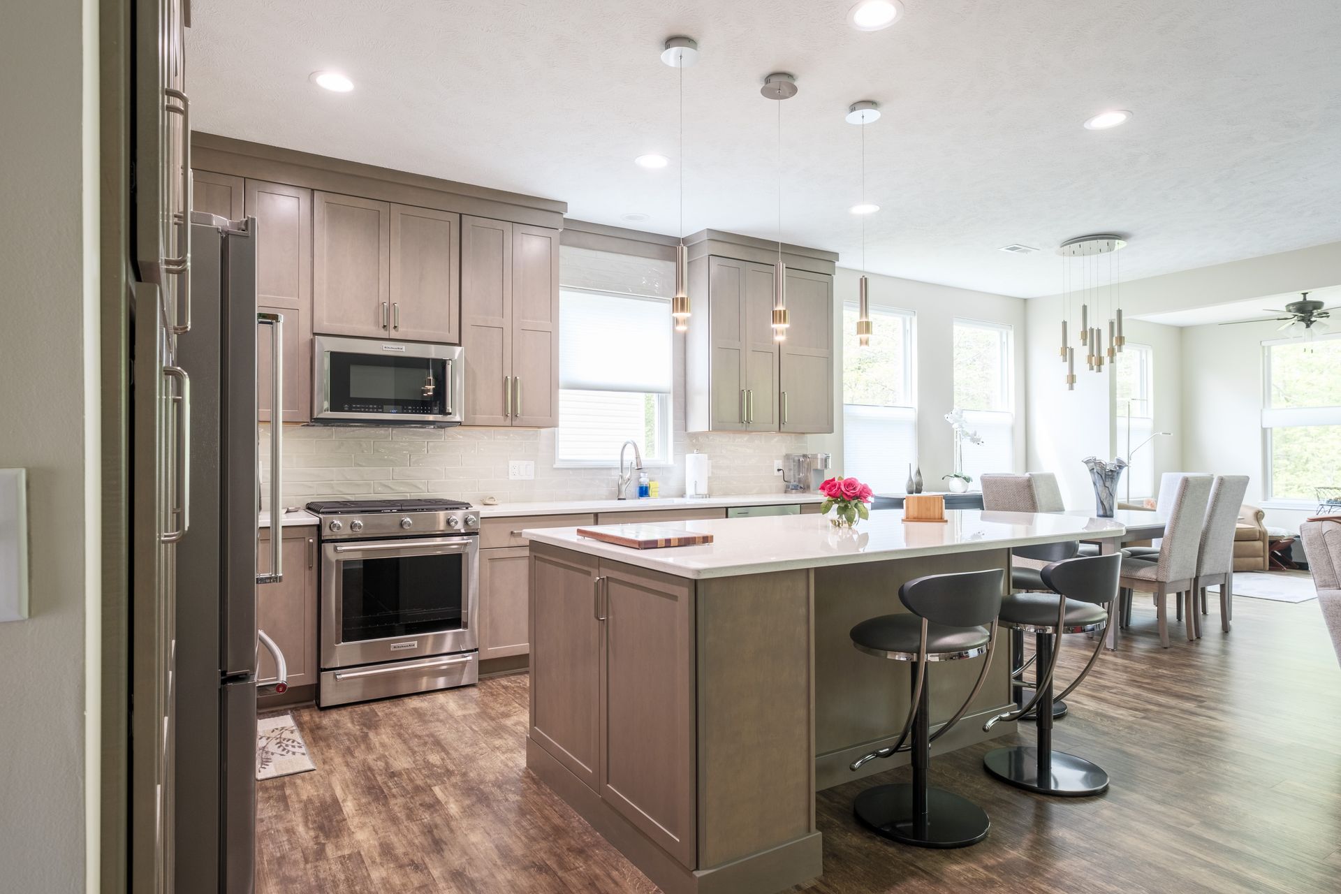 Modern kitchen with taupe cabinets, stainless steel appliances, and an island with bar stools.