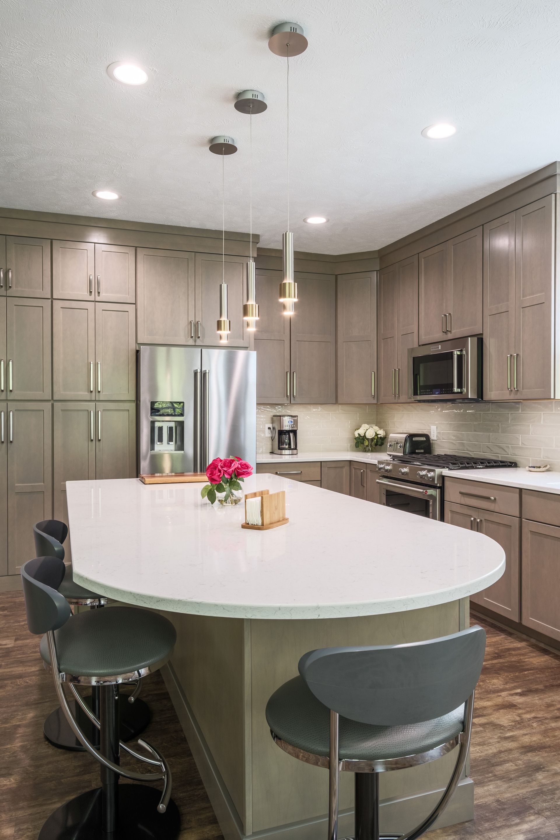 Modern kitchen with an island, cabinets, stainless steel appliances, and bar stools.