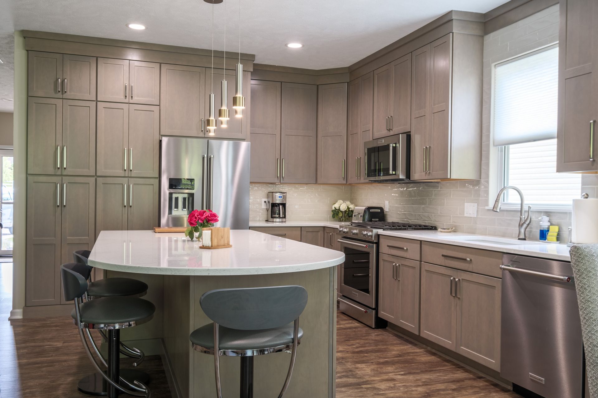 Modern kitchen with gray cabinets, white countertops, and an island with bar stools.