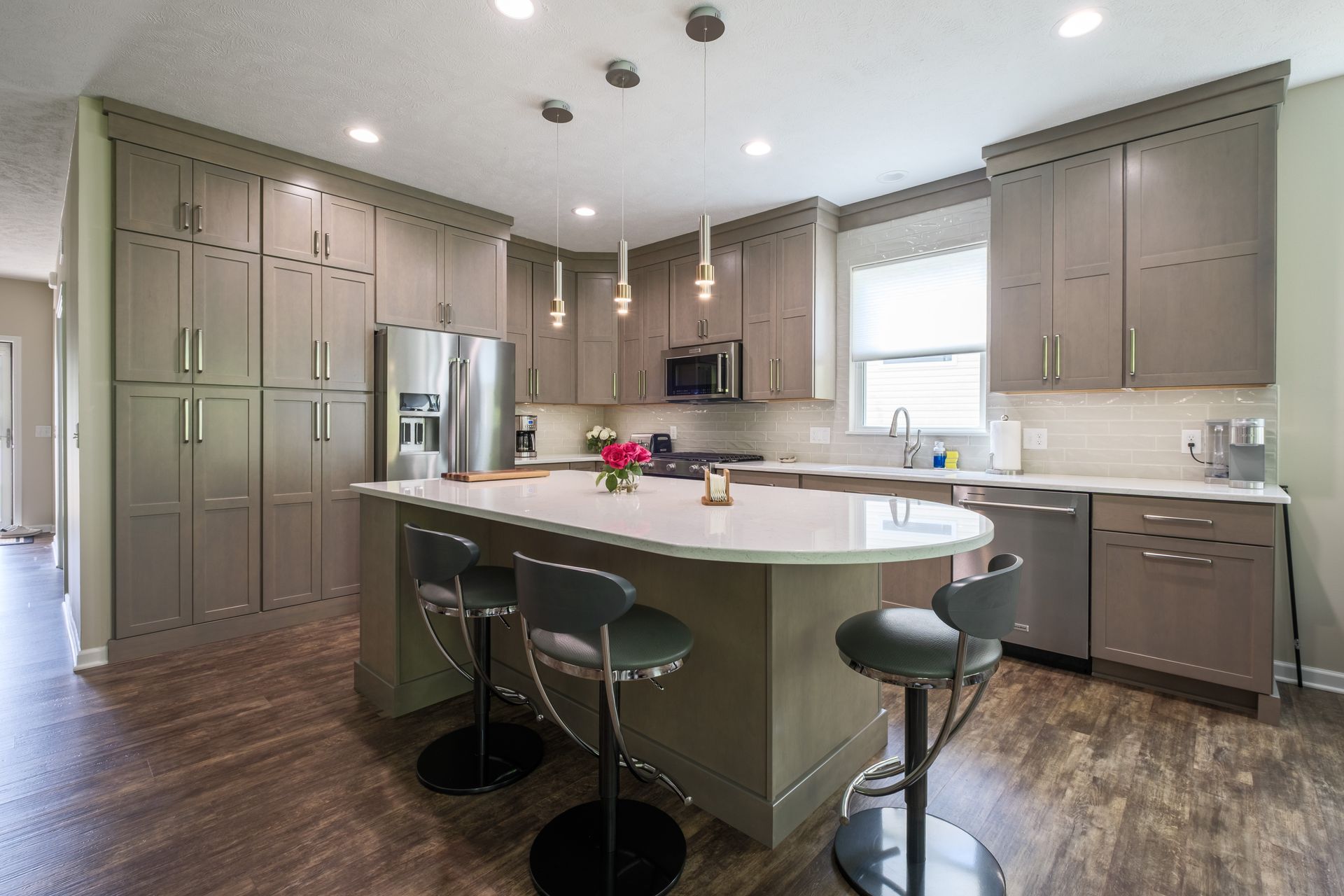 Modern kitchen with gray cabinets, white countertops, and a central island with stools.