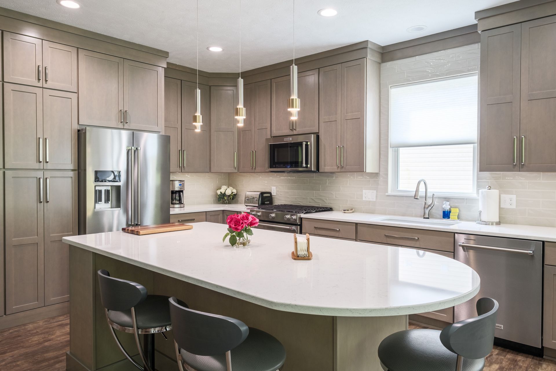 Modern kitchen with gray cabinets, white island, and stainless steel appliances.