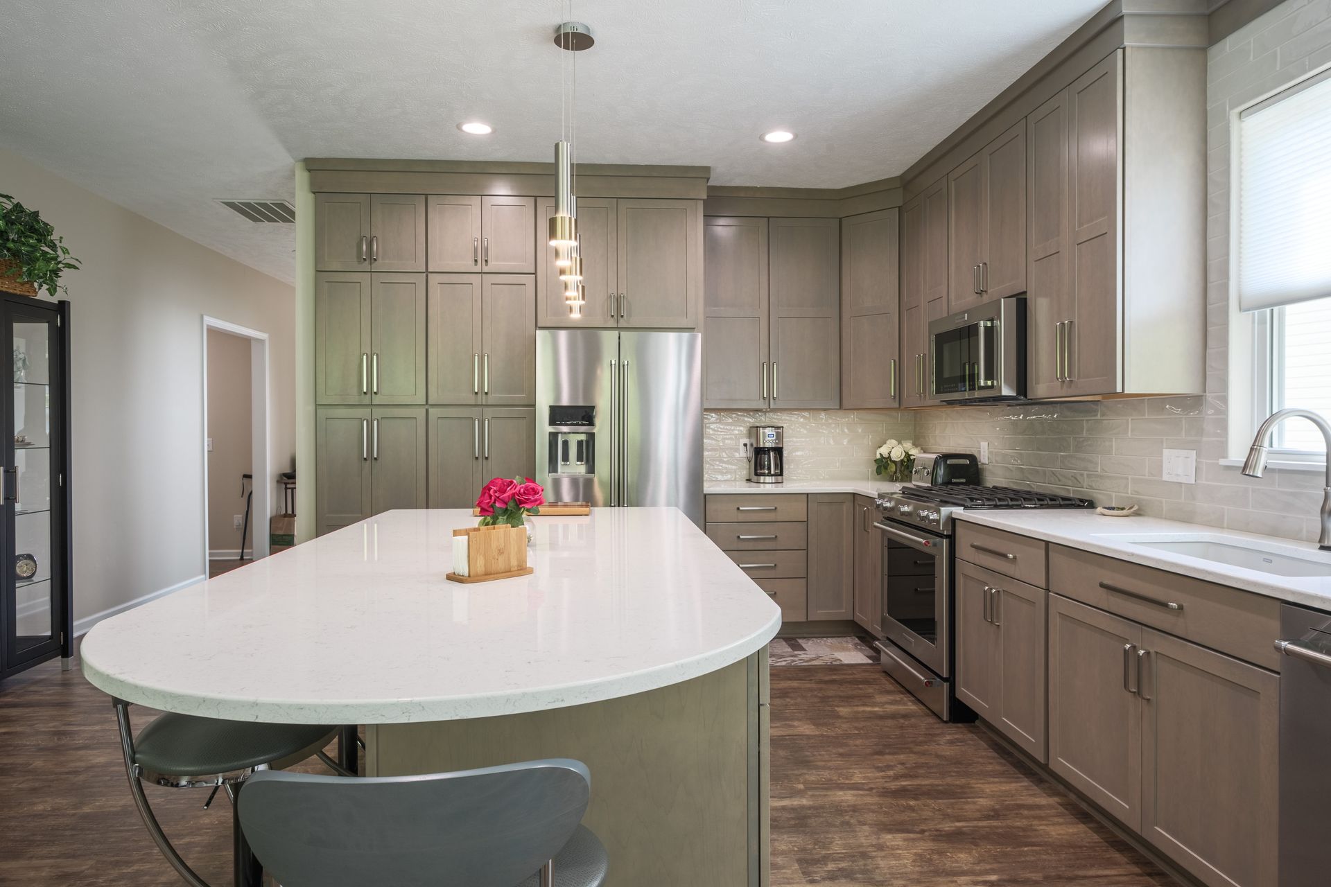 Modern kitchen with gray cabinets, white island, and stainless steel appliances.
