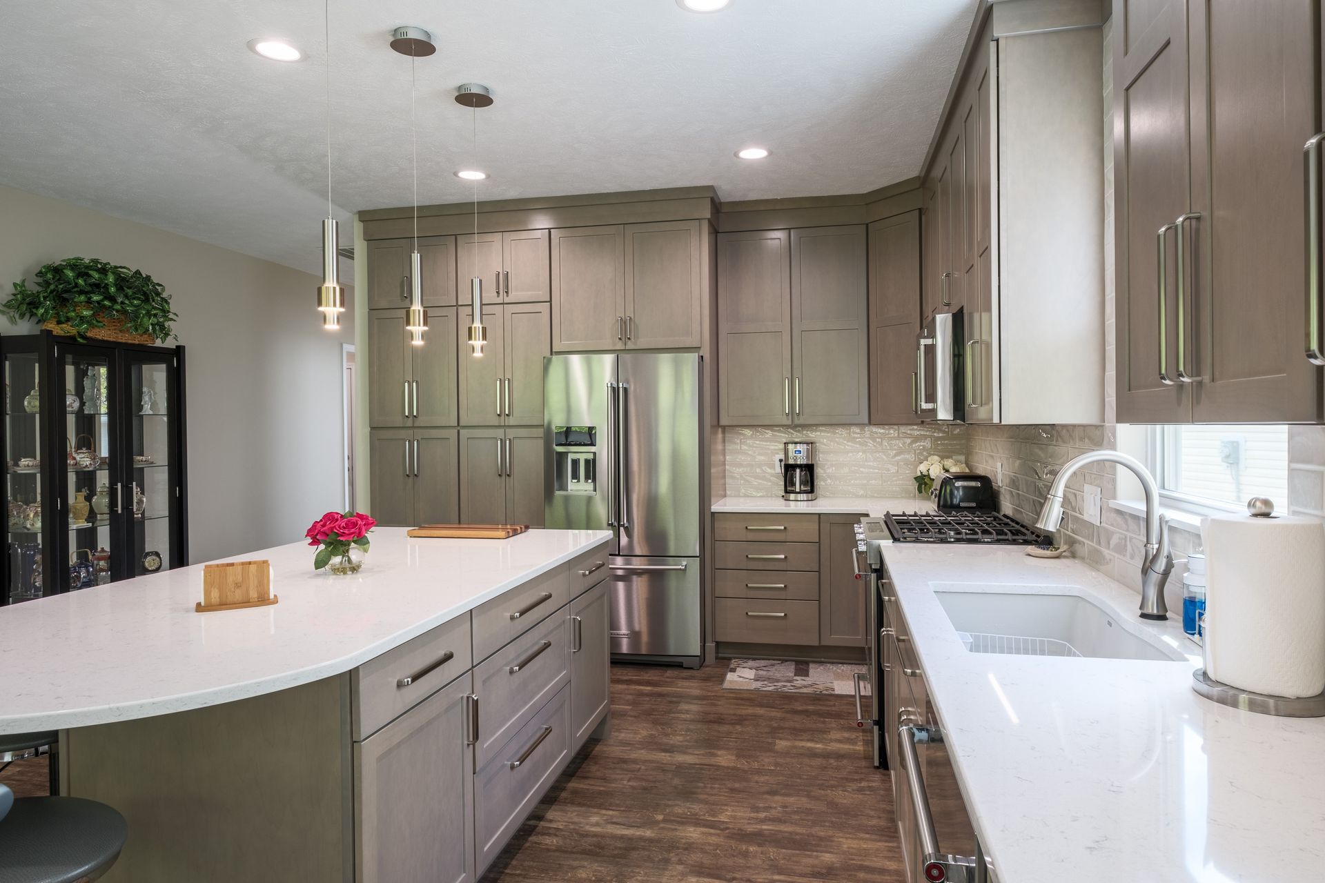 Modern kitchen with gray cabinets, stainless steel appliances, and white countertops.