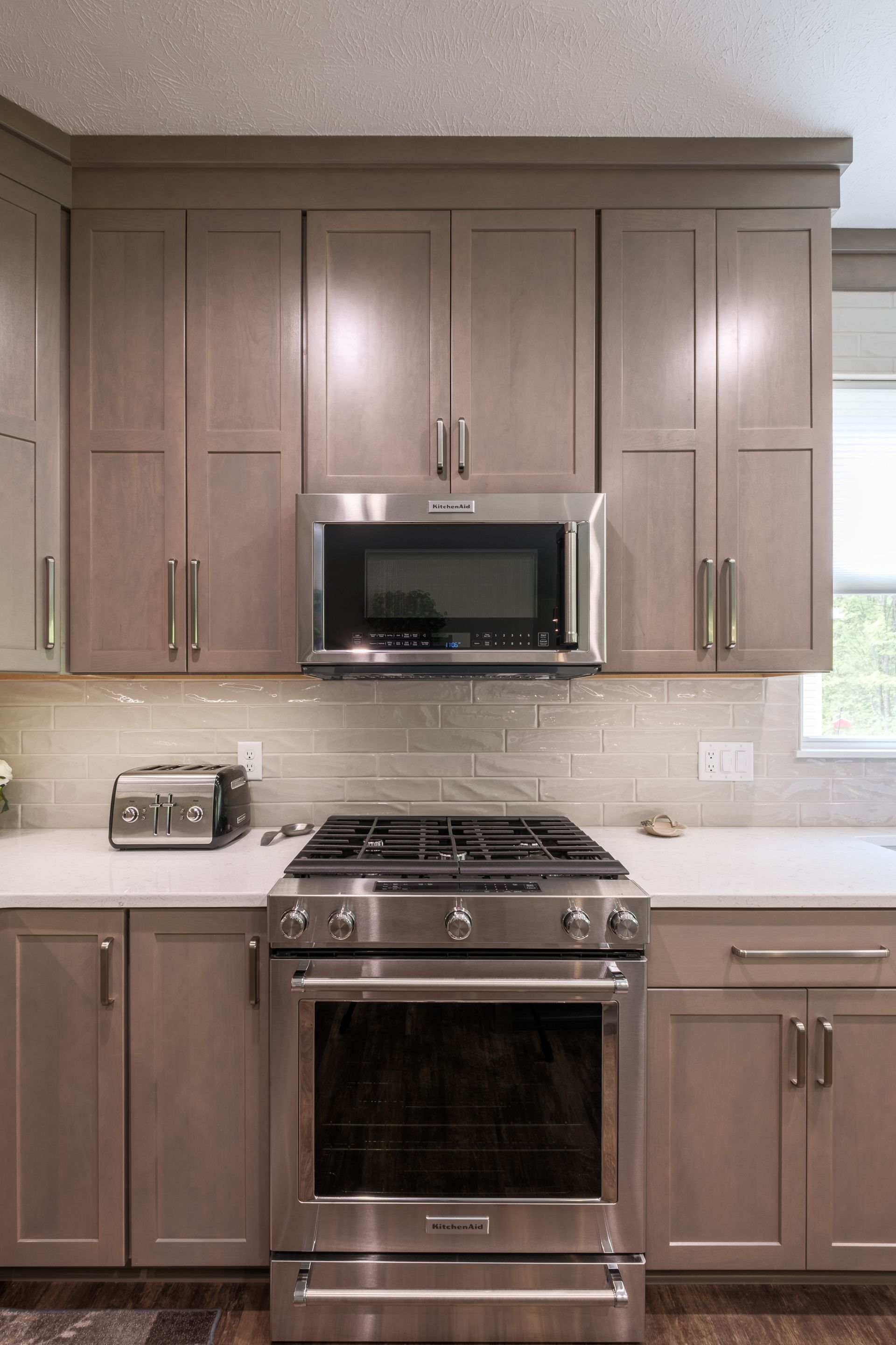 Kitchen with gray cabinets, stainless steel appliances, and a light-colored backsplash.