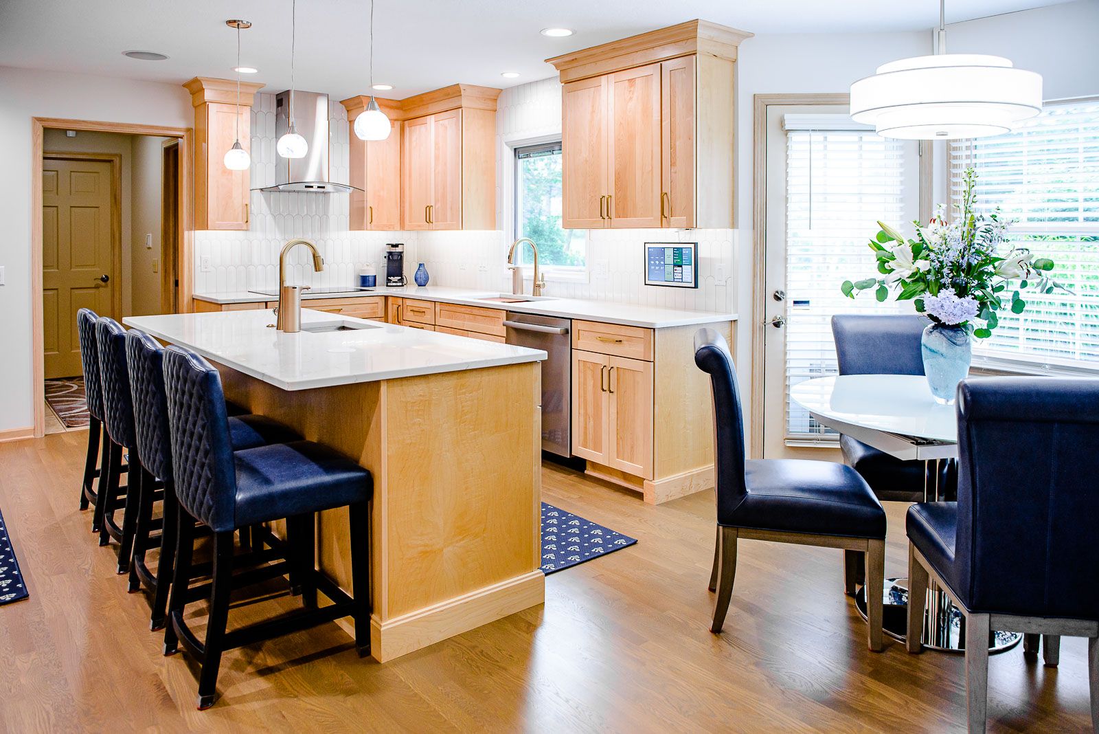 A kitchen with wooden cabinets , a large island , a table and chairs.