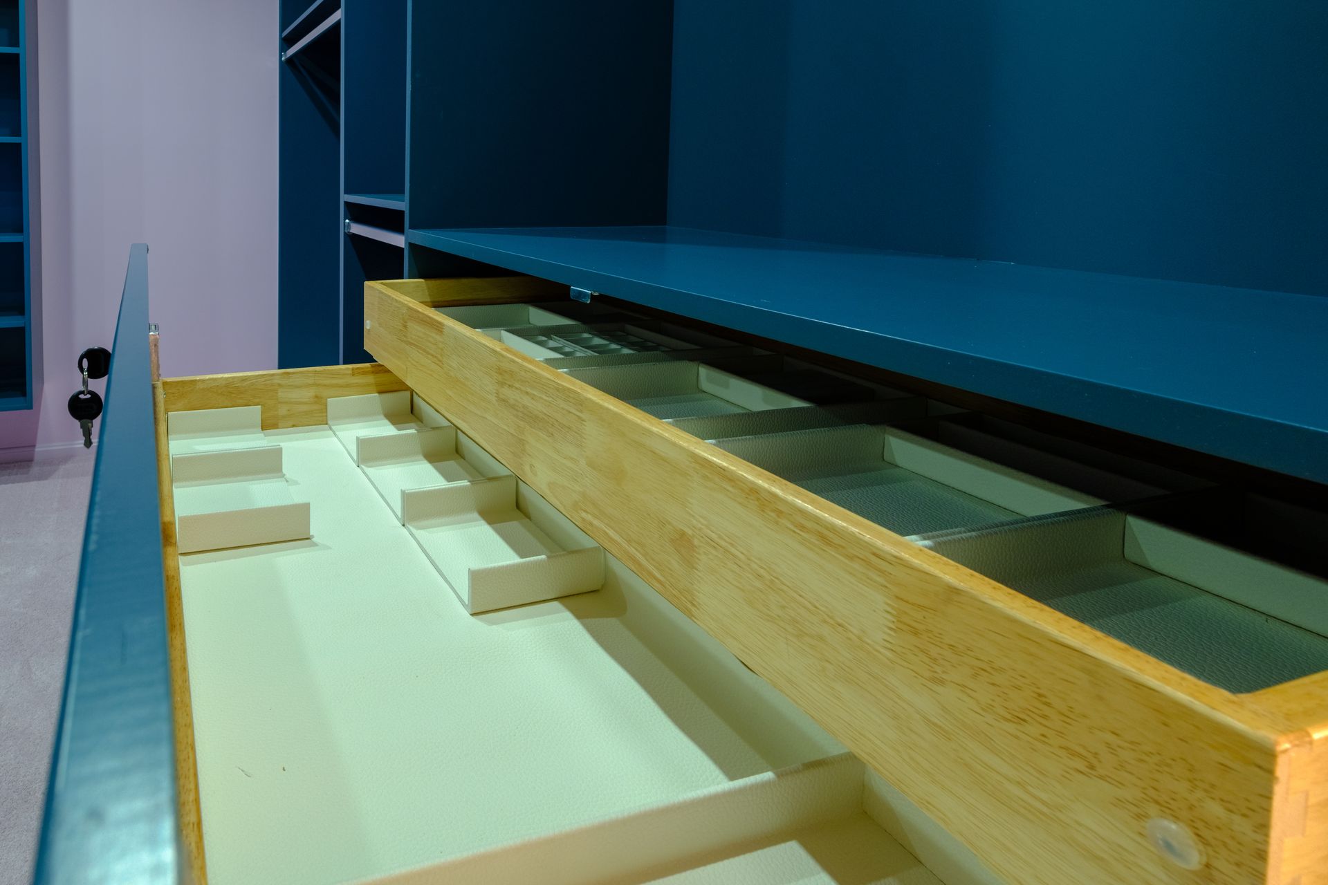 Open turquoise drawer revealing wooden dividers and a glass bottom.
