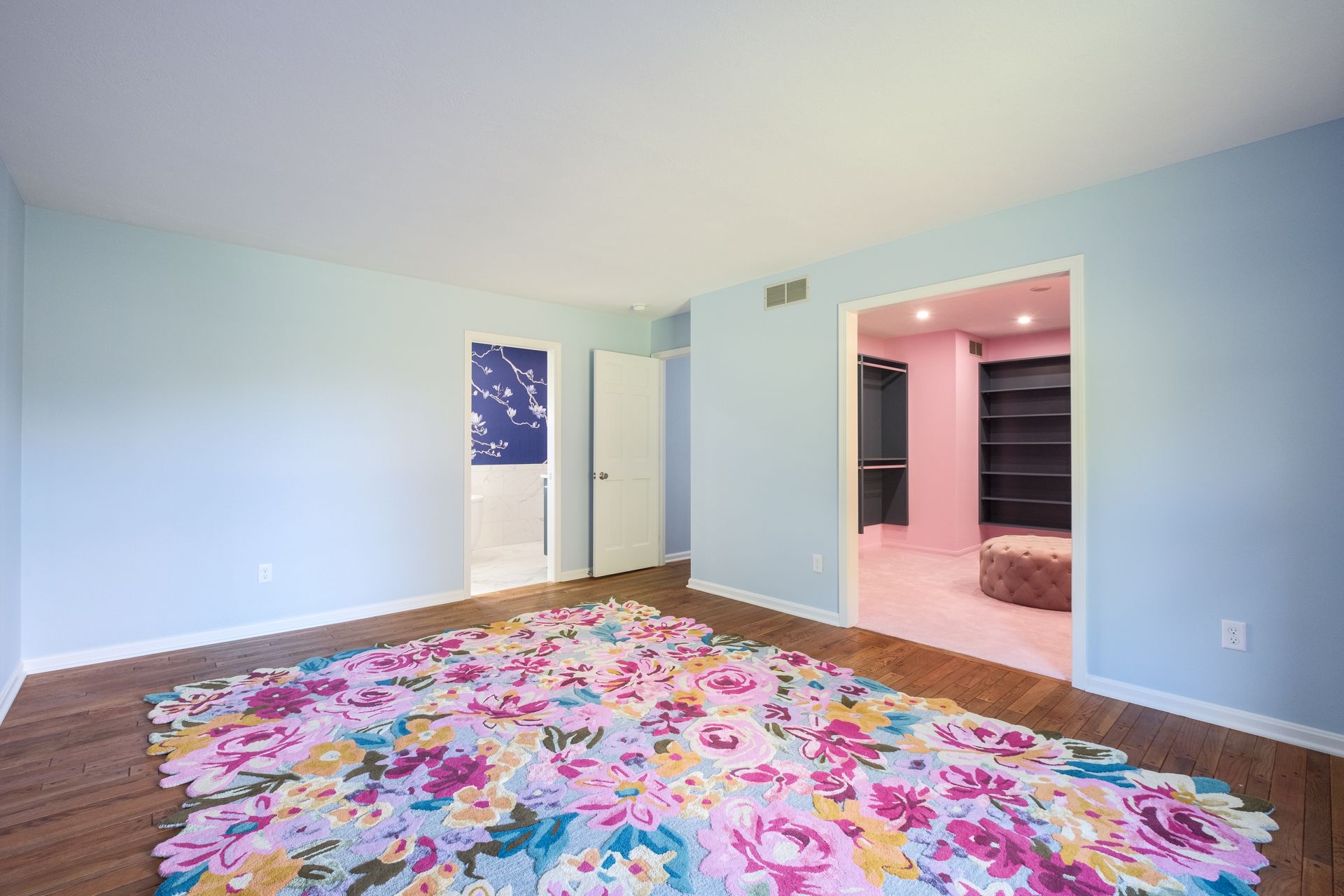 Room with blue walls, floral rug, and an open doorway to a walk-in closet.
