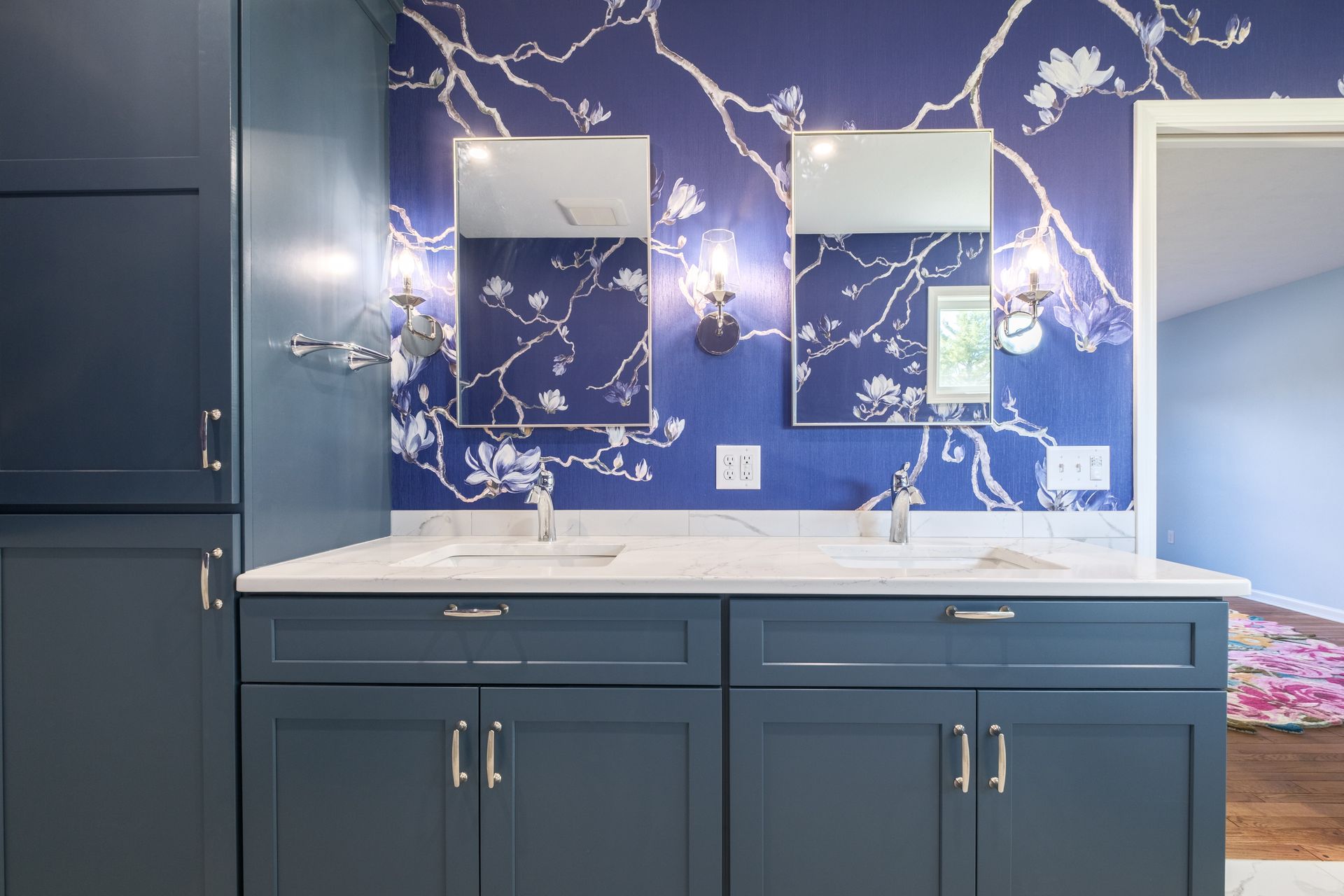 Blue bathroom with double vanity, floral wallpaper, and rectangular mirrors.