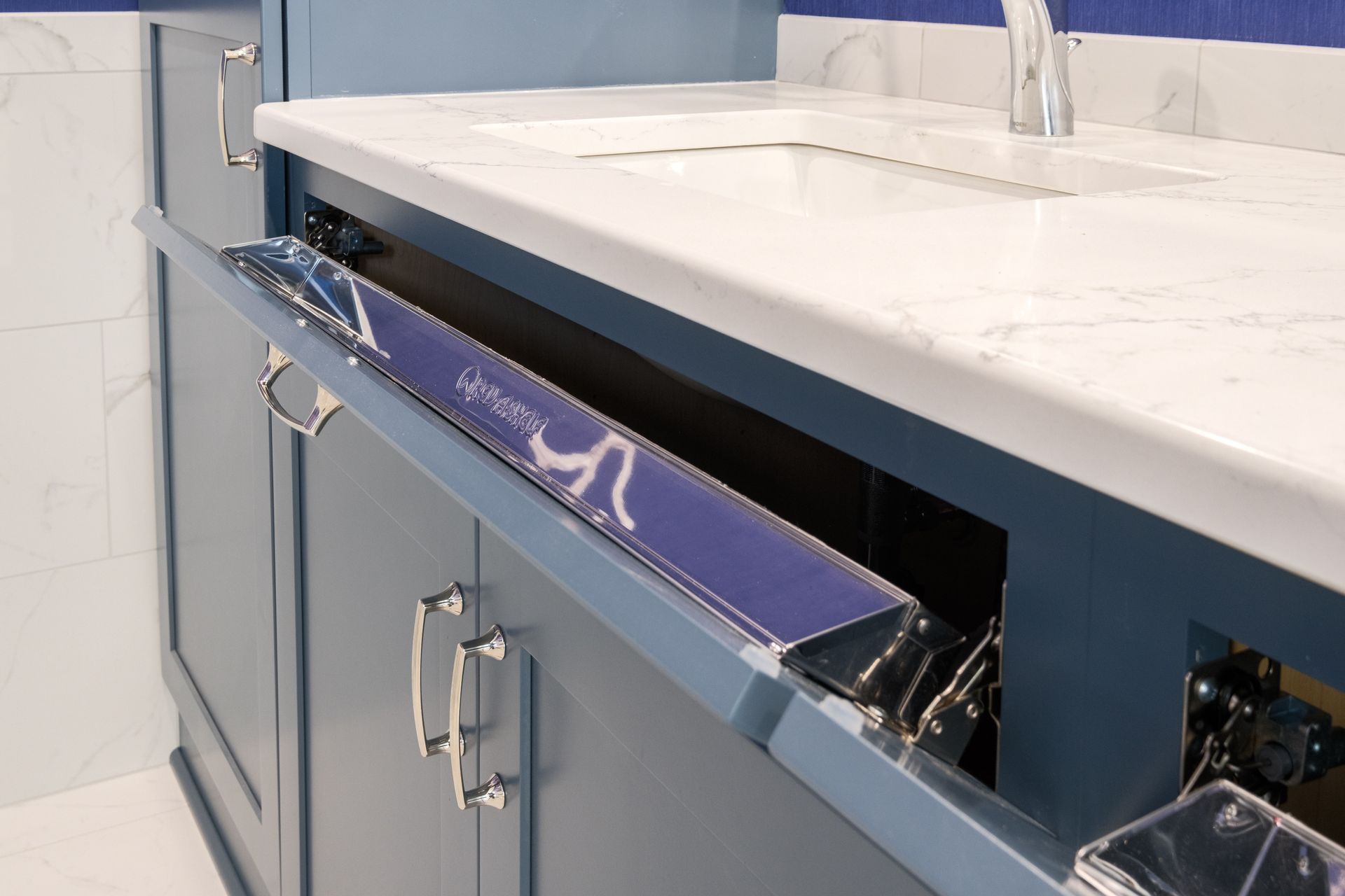 Blue bathroom vanity with a pull-out drawer under a white countertop and sink.