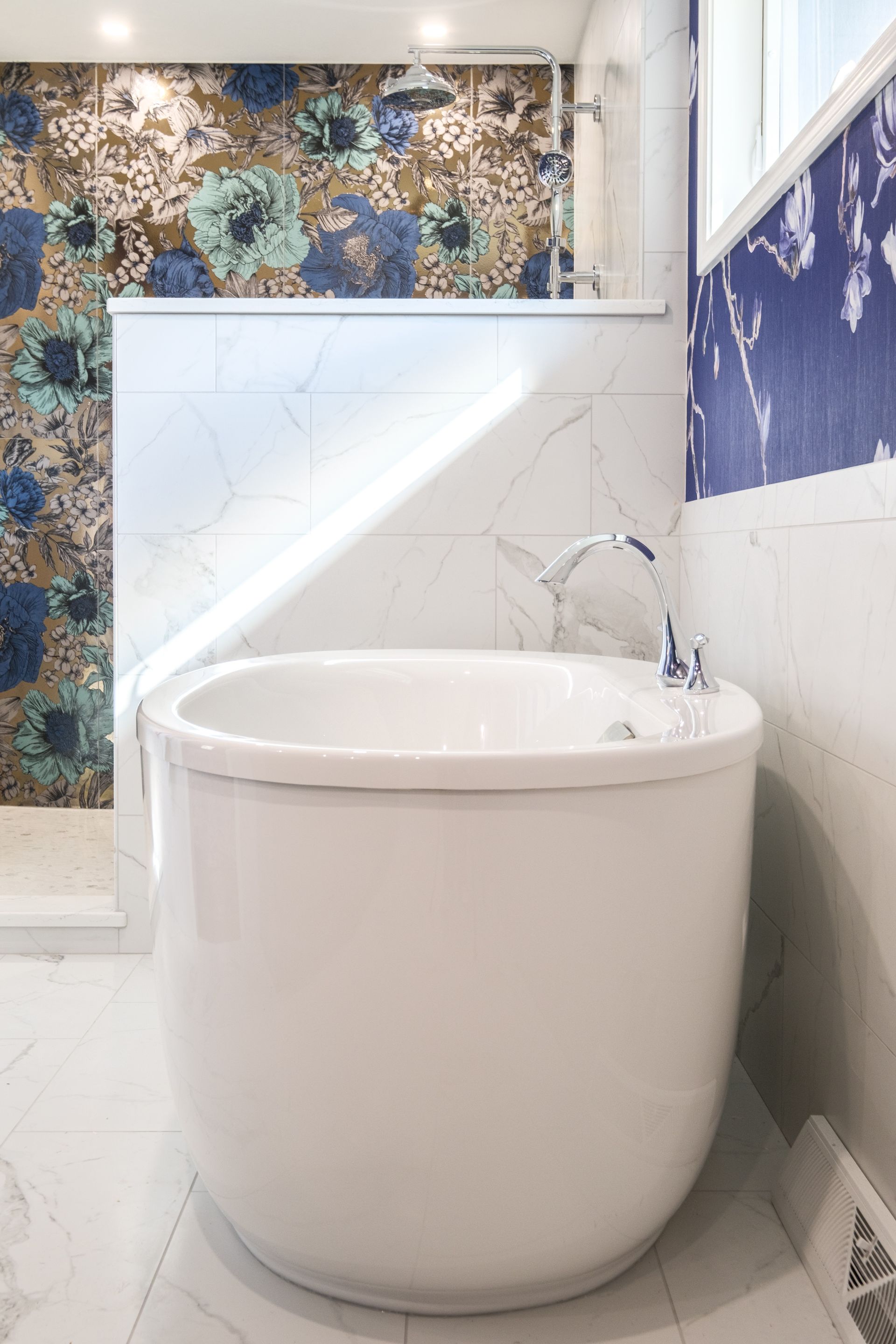 White soaking tub in a bathroom with floral tile and marble walls.