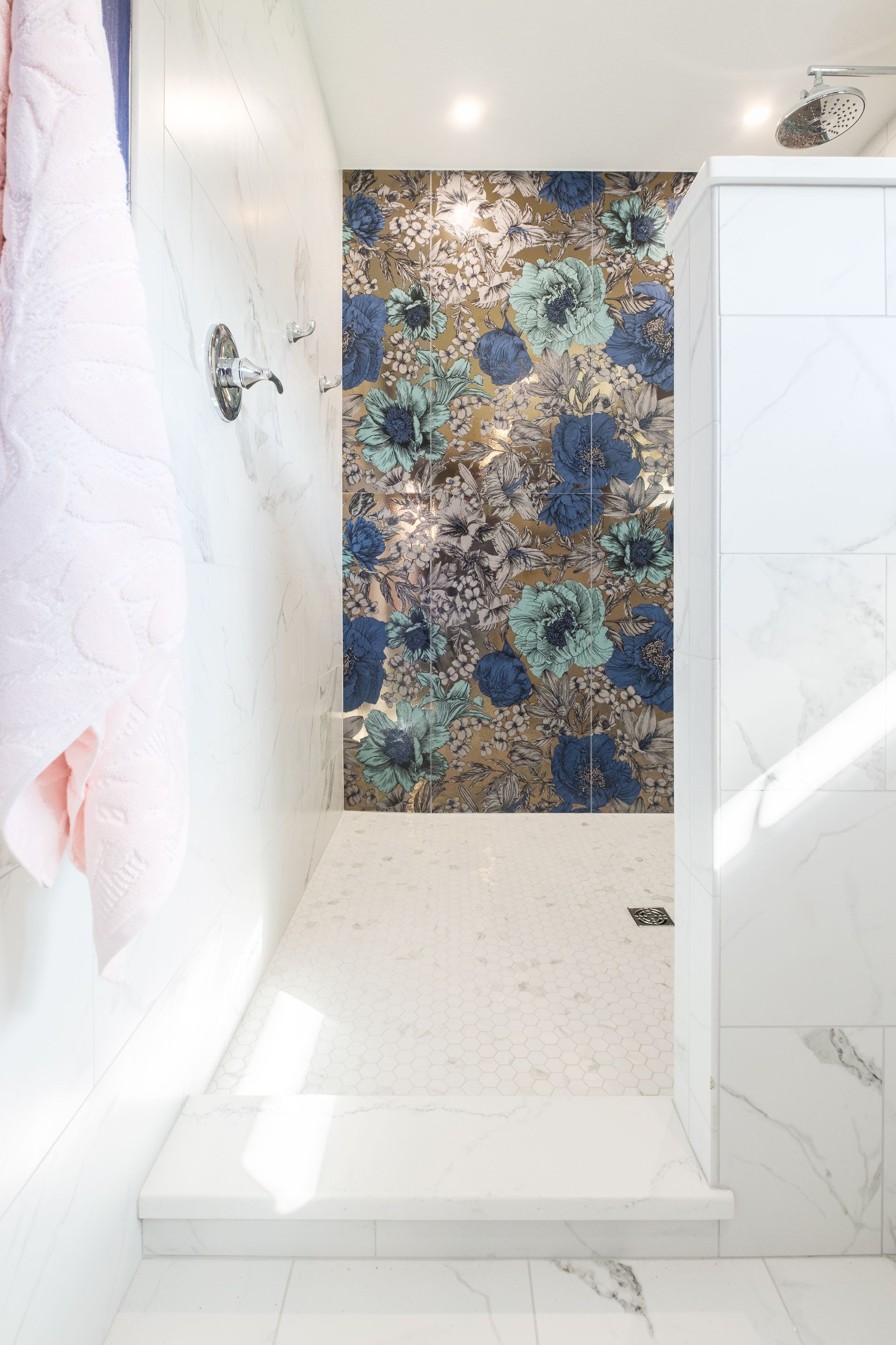 Shower with mosaic tile wall, white marble, and light entering from the side.