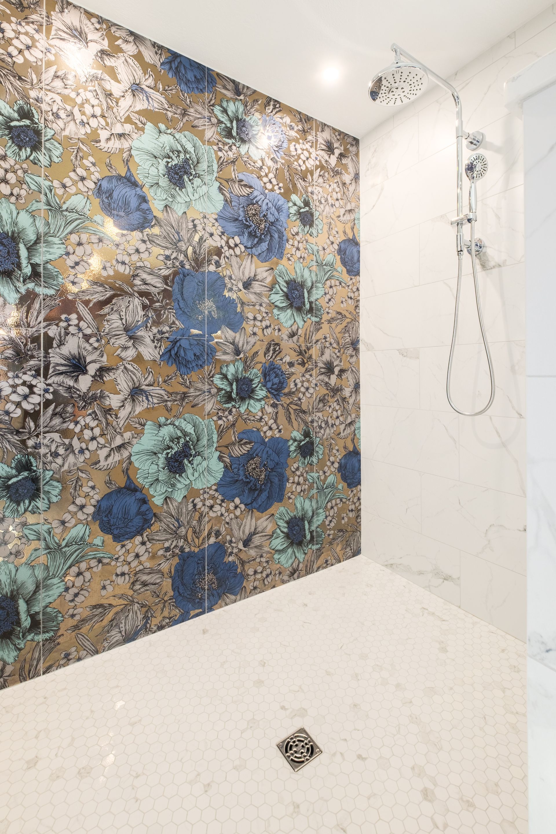 Shower with floral mosaic accent wall, white marble, and rain showerhead.