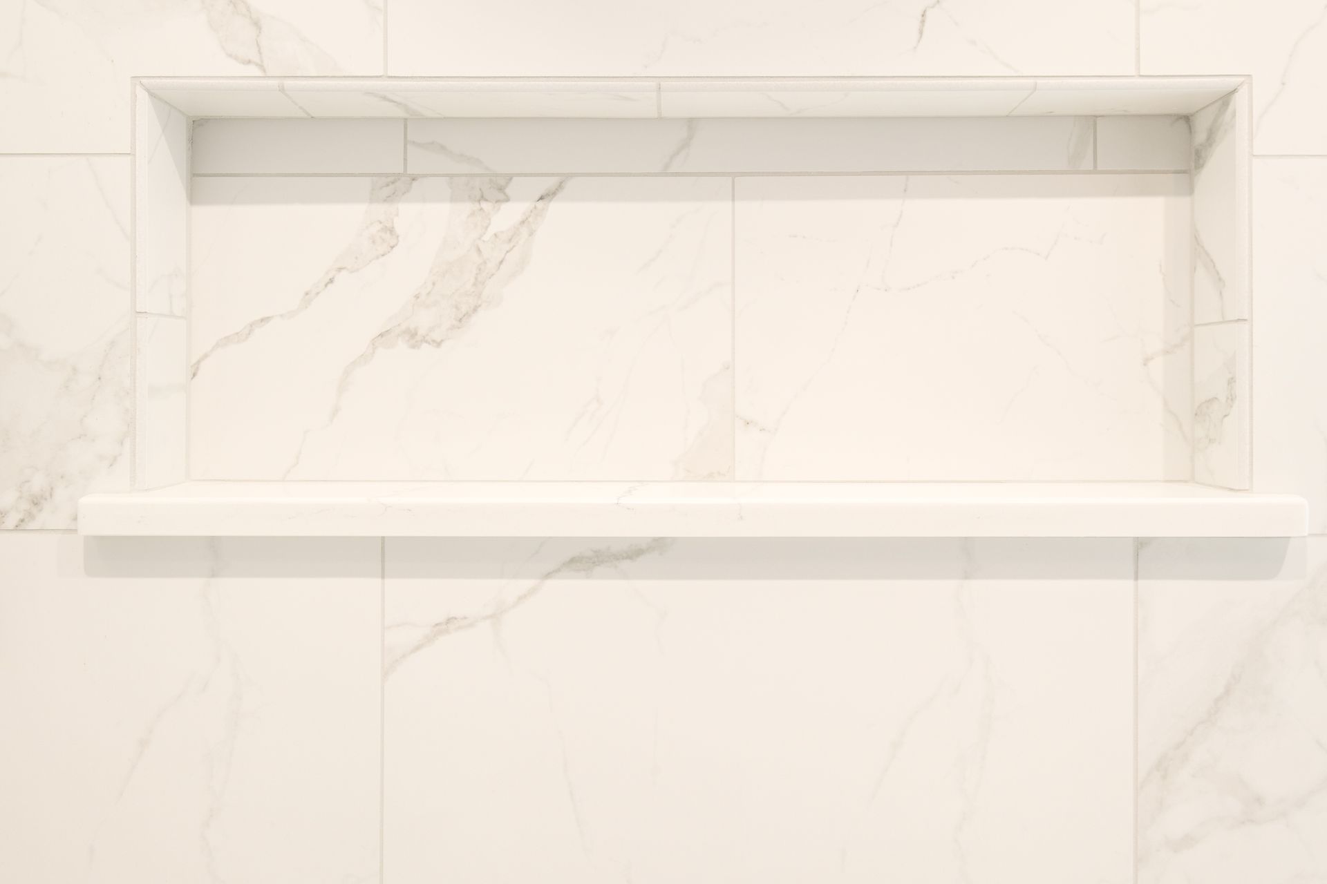 Recessed marble shelf in a tiled shower wall.