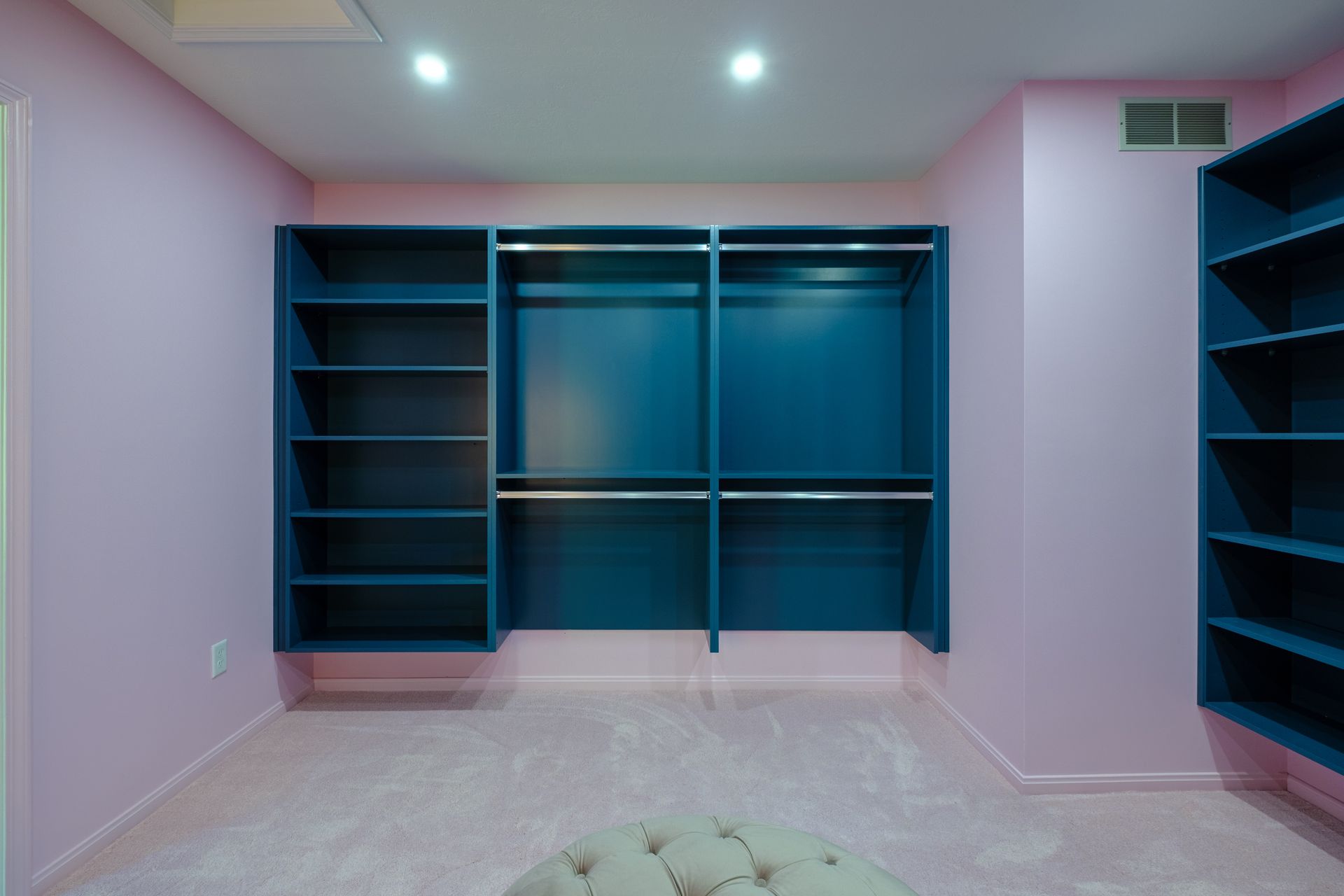 Walk-in closet with blue shelving and lilac walls and carpet.