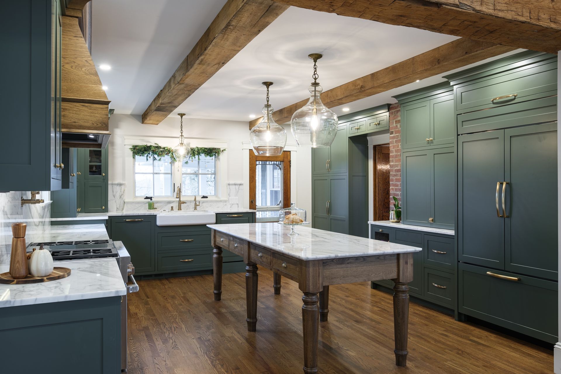Green kitchen with wood beams, island, marble countertops, and cabinets.