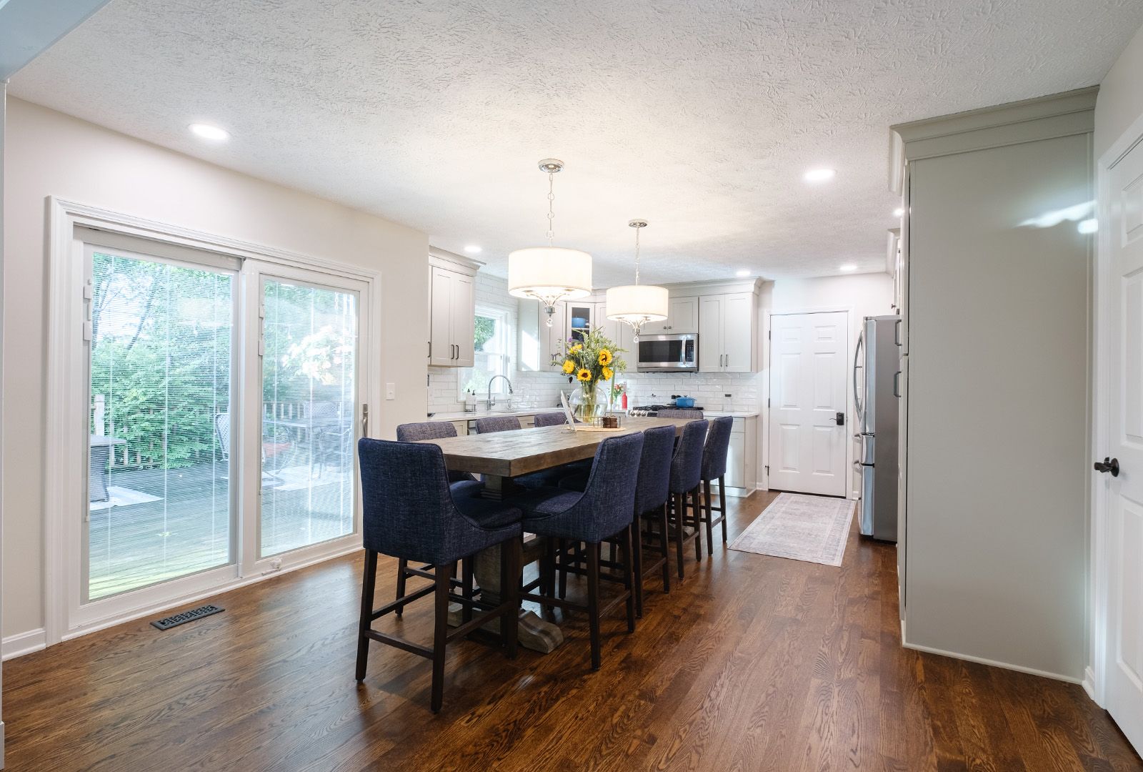 A dining room table and chairs in a kitchen with sliding glass doors.