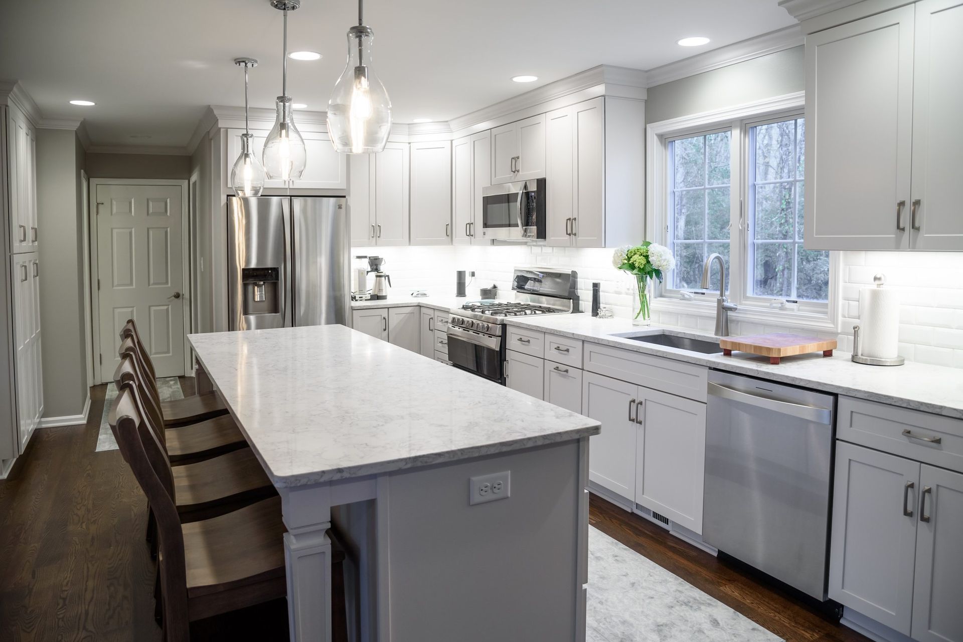 A kitchen with white cabinets , stainless steel appliances , and a large island.