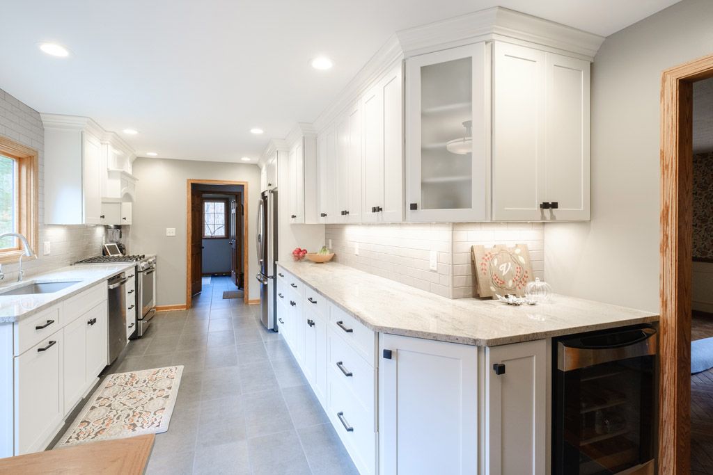 A kitchen with white cabinets , granite counter tops , and stainless steel appliances.