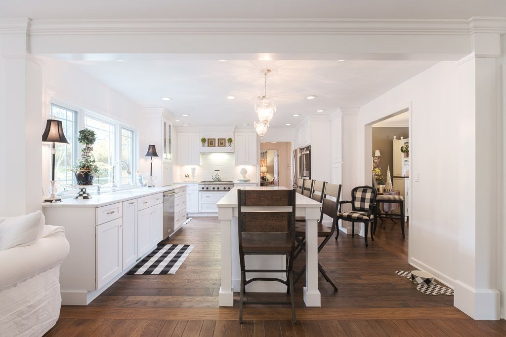 A kitchen with white cabinets , wooden floors , and a large island.